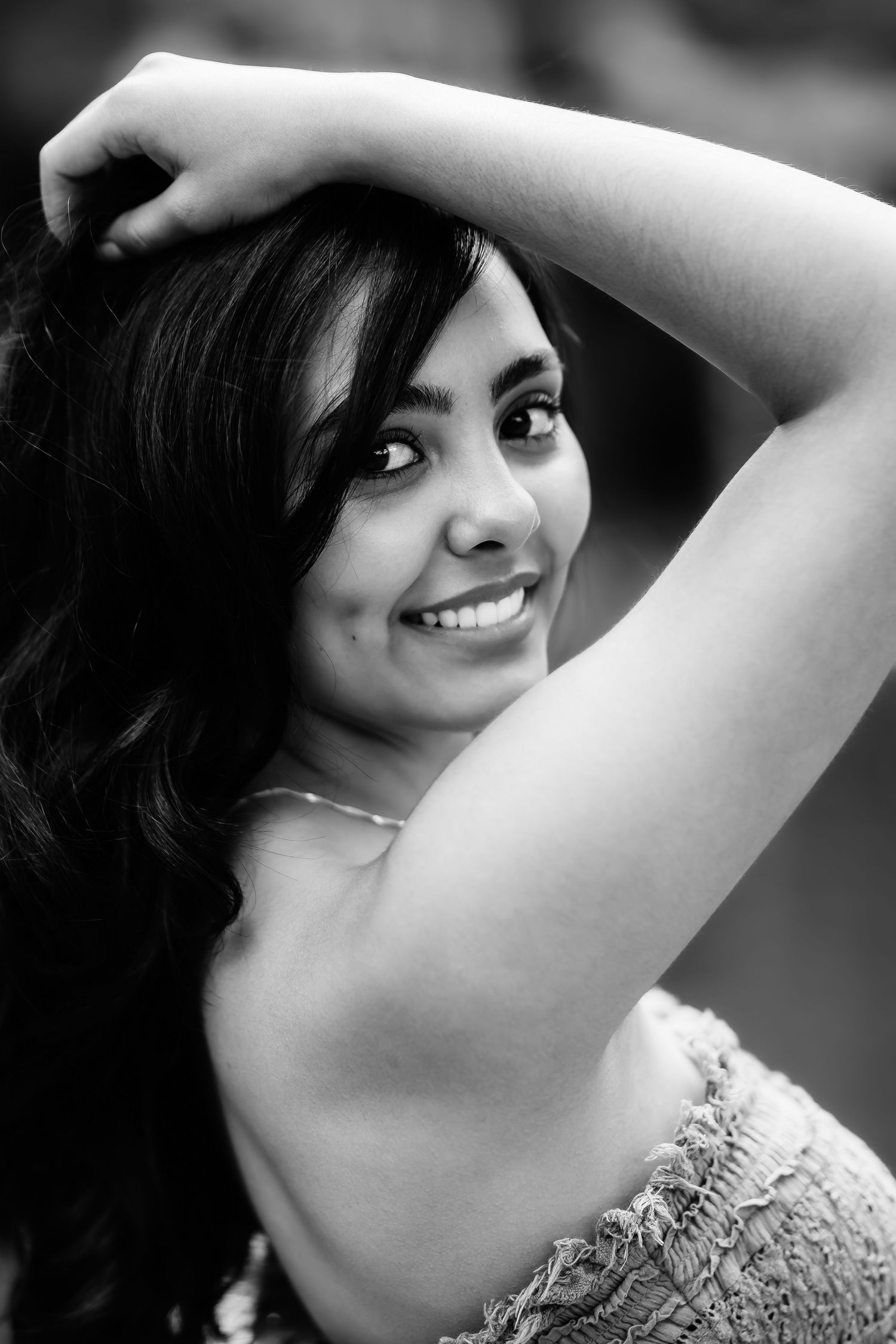 Black and white portrait showing a graceful pose against a soft blurred background.