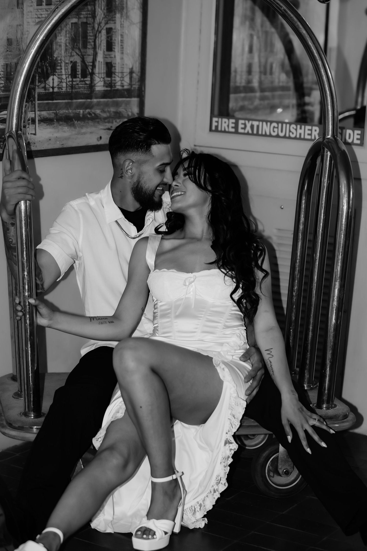 A black and white intimate portrait of a couple sharing a romantic moment in what appears to be a train car.