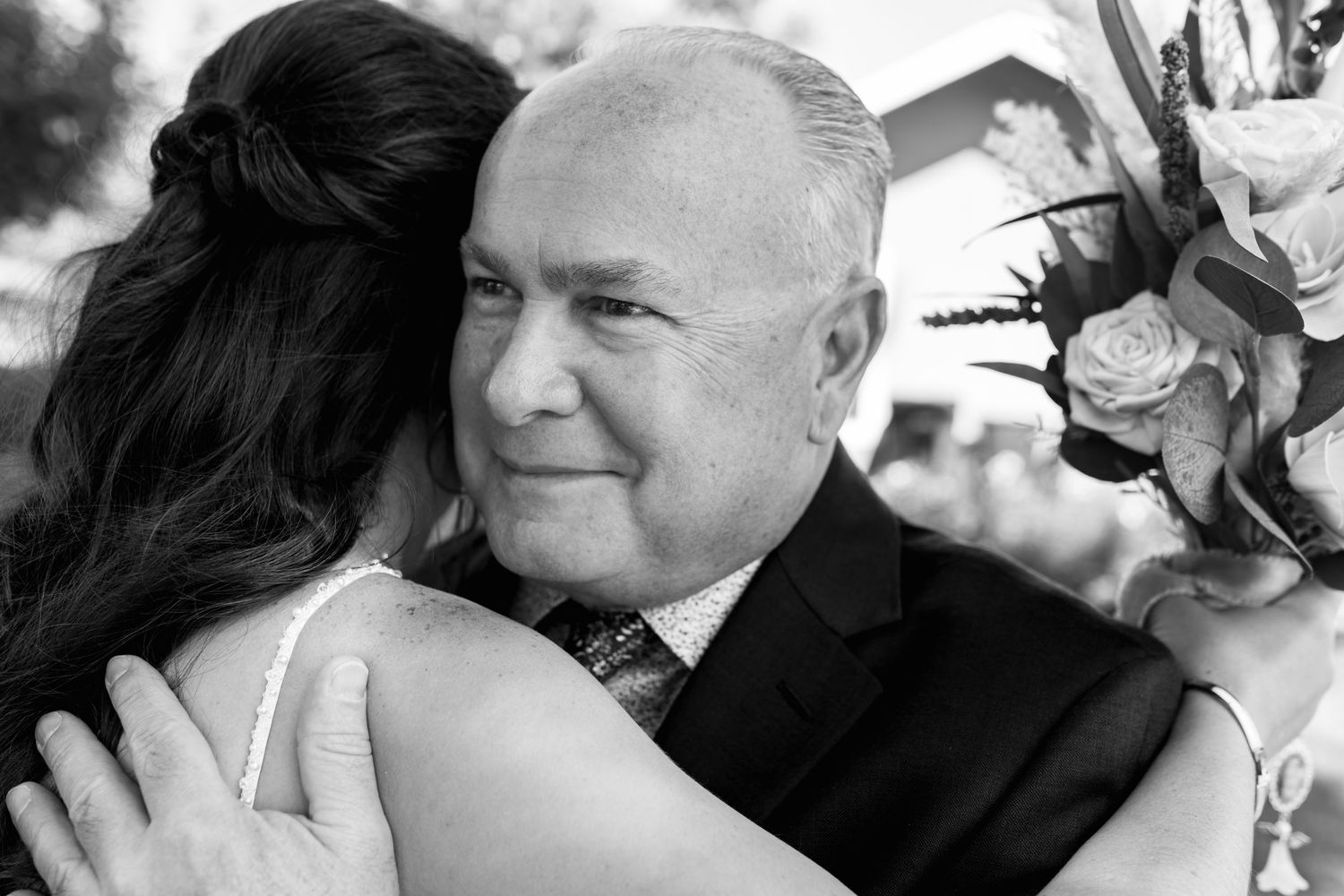 Black and white portrait of an emotional embrace at outdoor wedding.