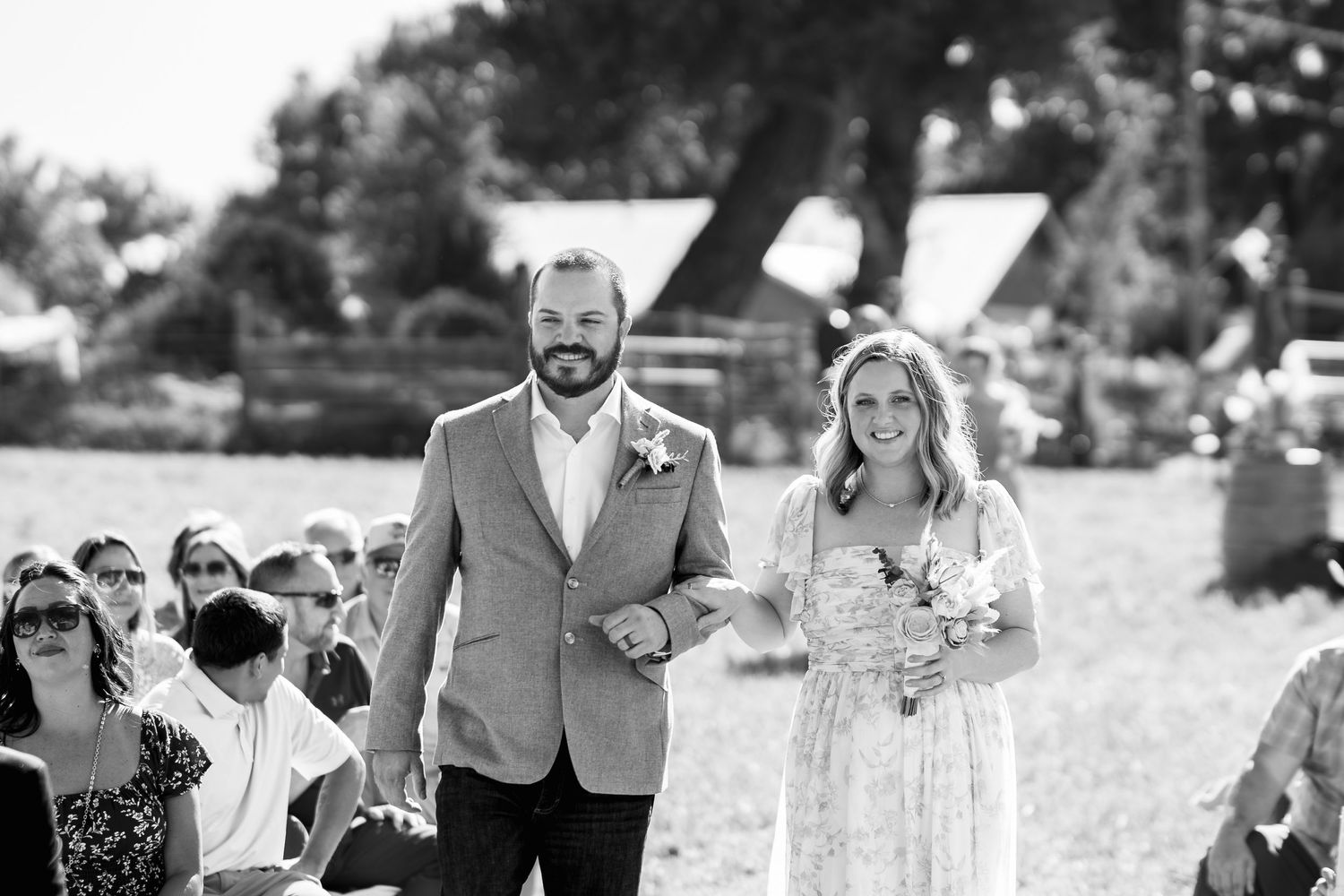 Wedding couple walking down aisle outdoors in black and white photograph.