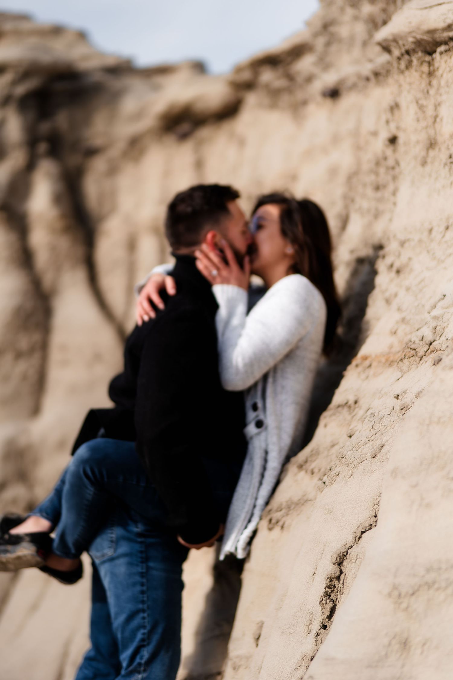 A romantic moment shared between two people against weathered rock formations in natural light.