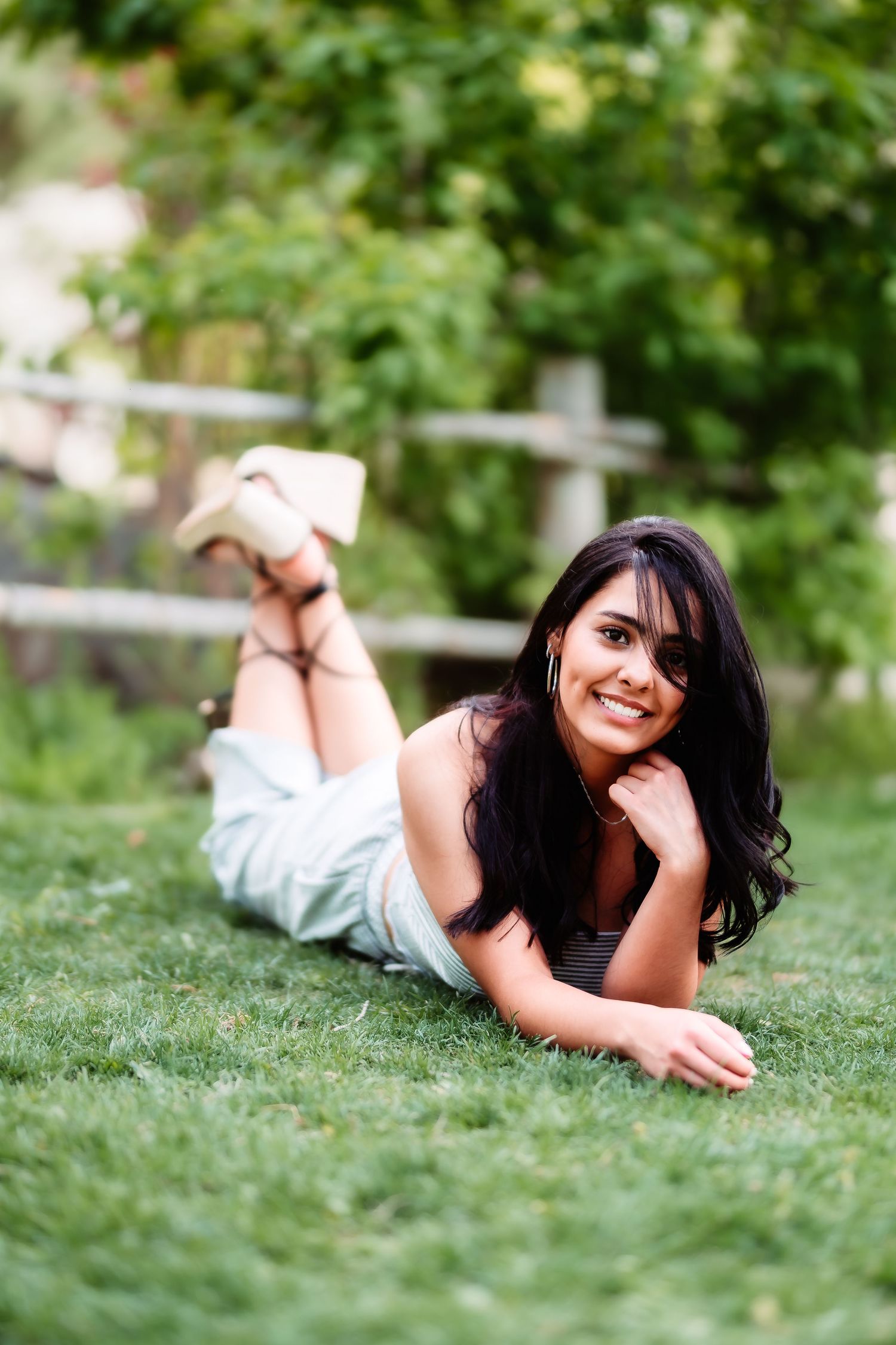 Portrait of someone lying on grass in a white outfit with natural green background.