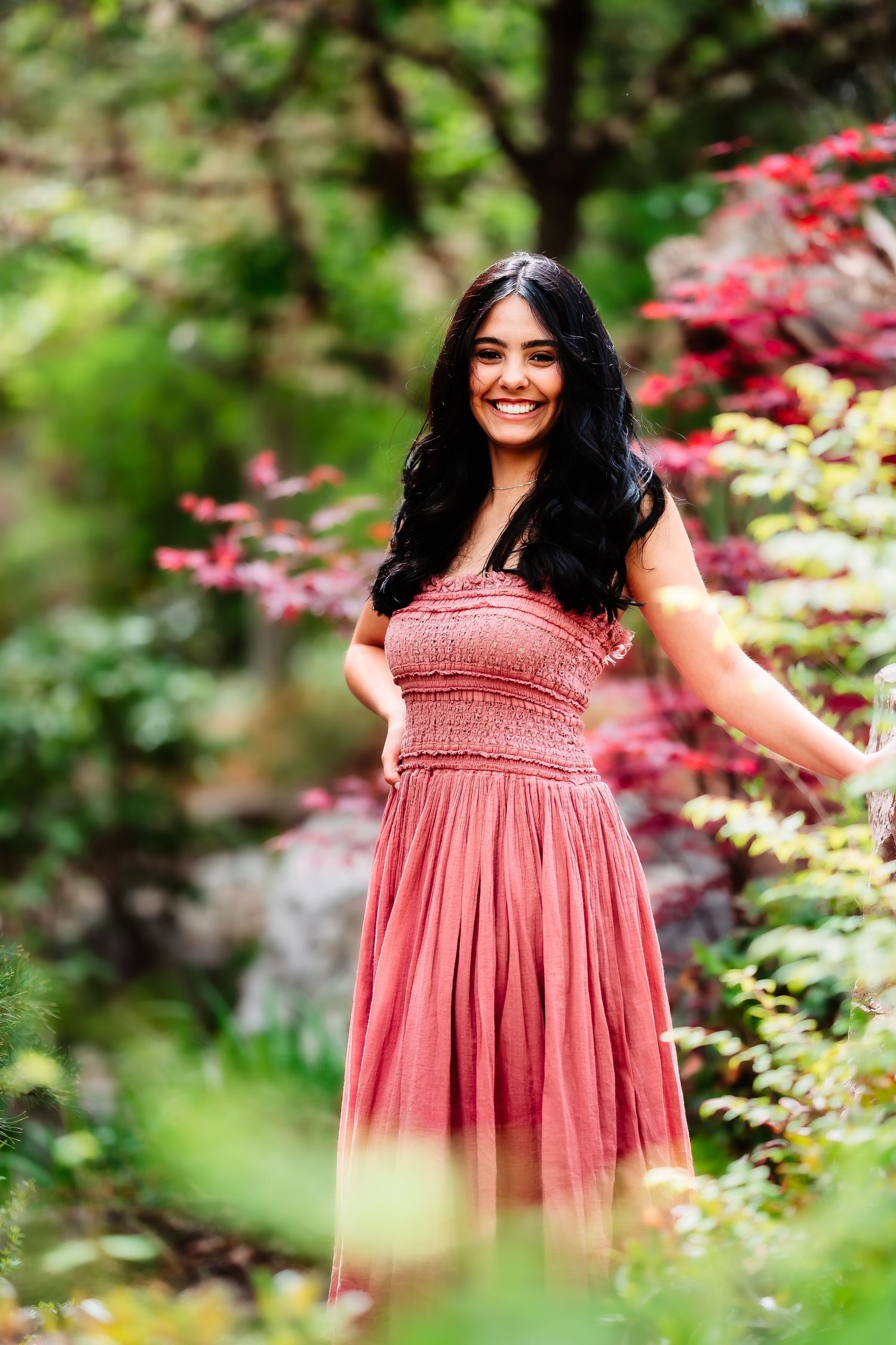 A joyful garden portrait featuring a coral strapless dress amid colorful foliage.