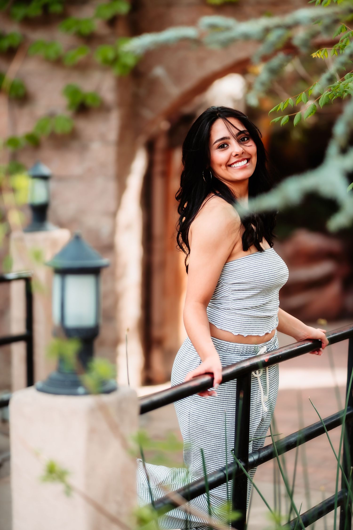 Person in casual gray attire leans against railing near decorative lantern with brick architecture behind.