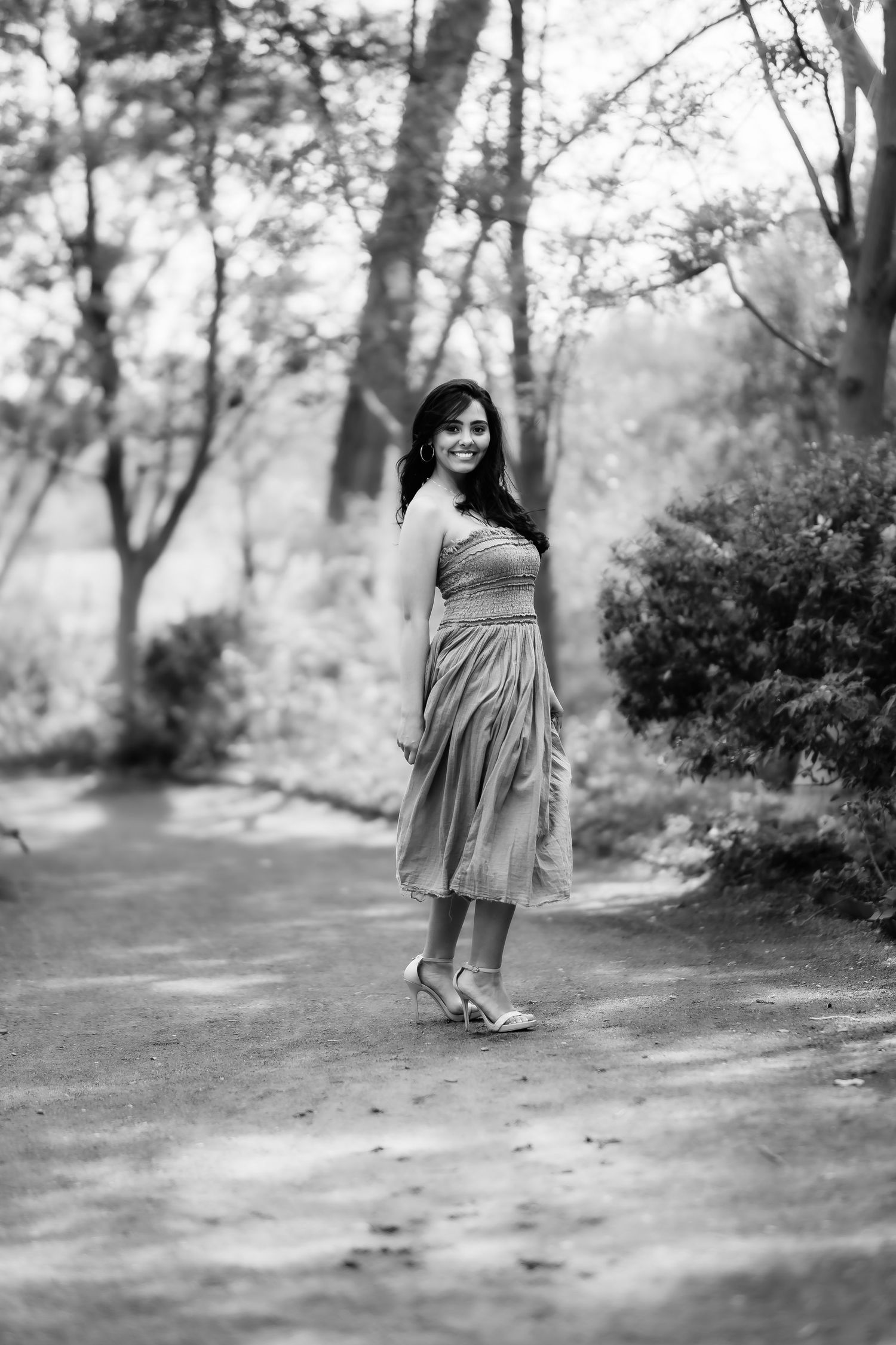 Black and white portrait on a wooded path wearing a flowing dress.