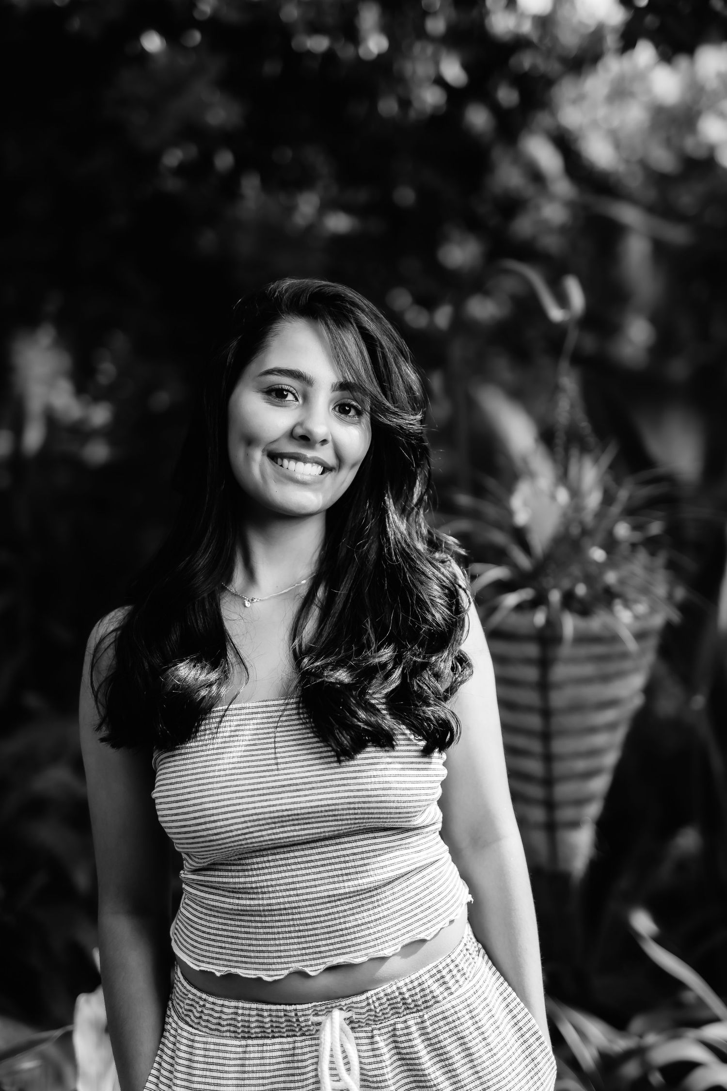 Black and white casual portrait in a garden setting with potted plants.