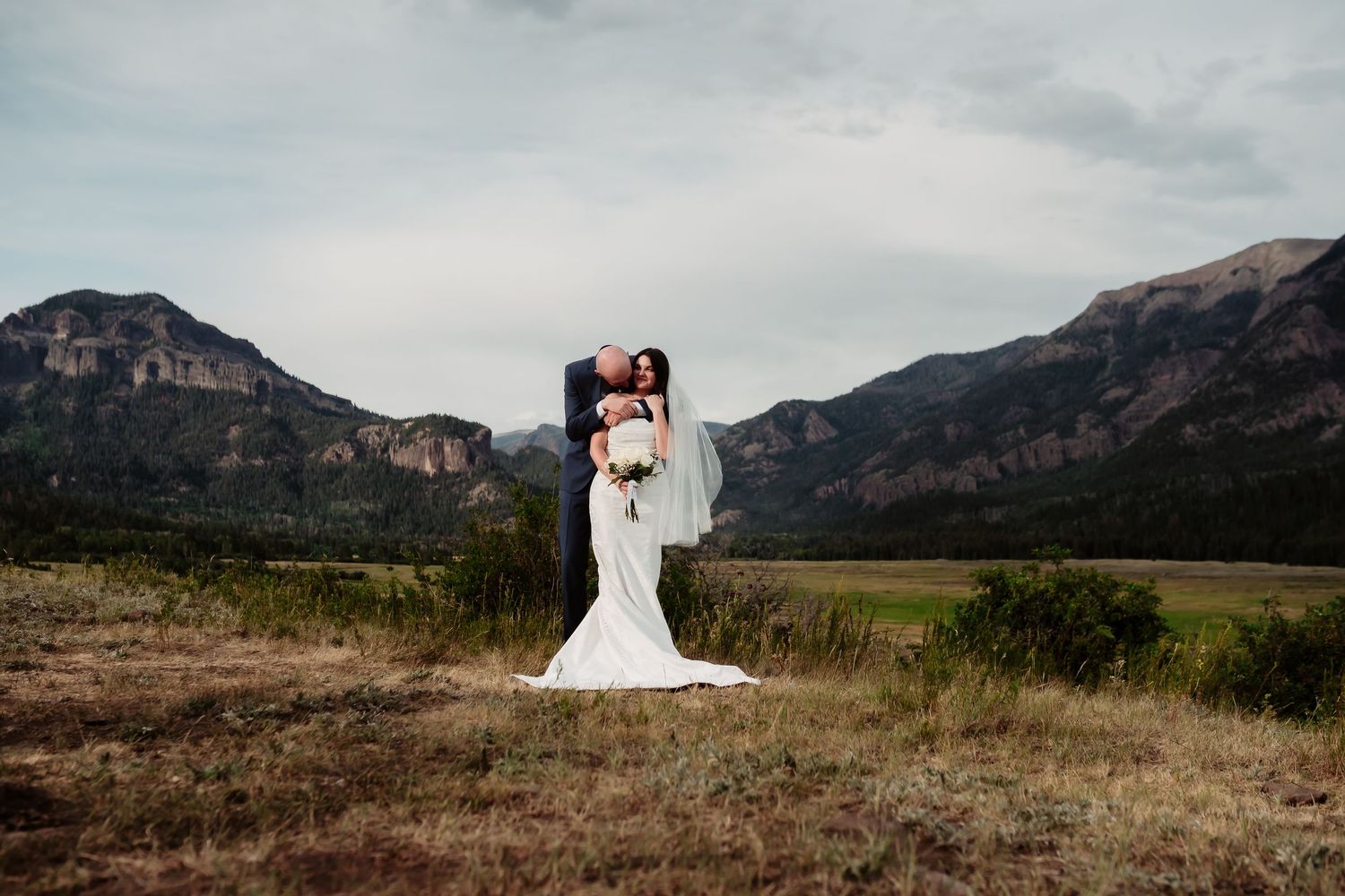 Scenic mountain wedding portrait with dramatic landscape background.