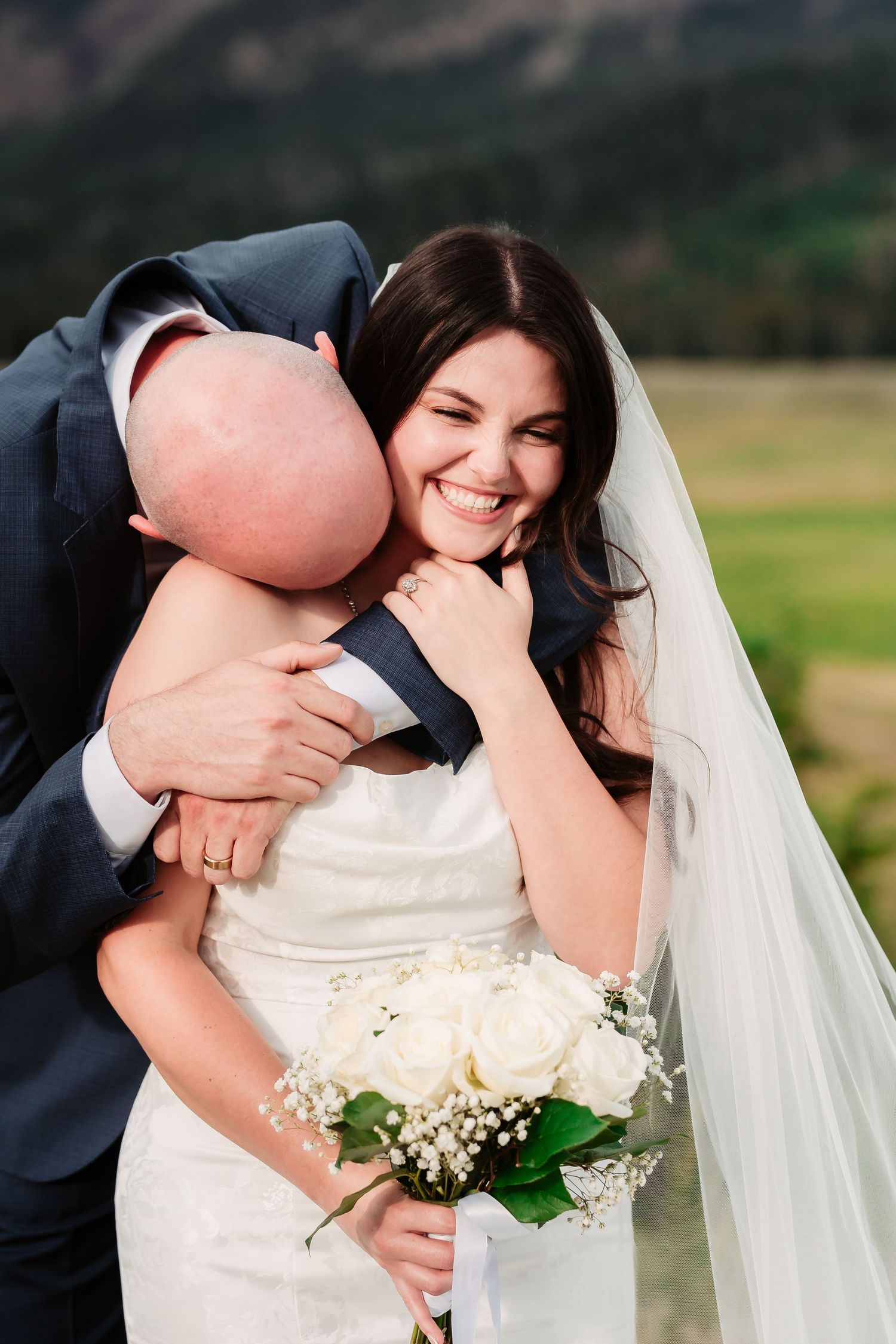 A candid moment of joy captured with white roses and a mountain vista in the background.