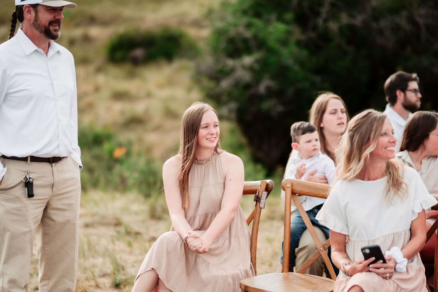 Wedding ceremony with wooden chairs set up outdoors against a scenic mountain backdrop.