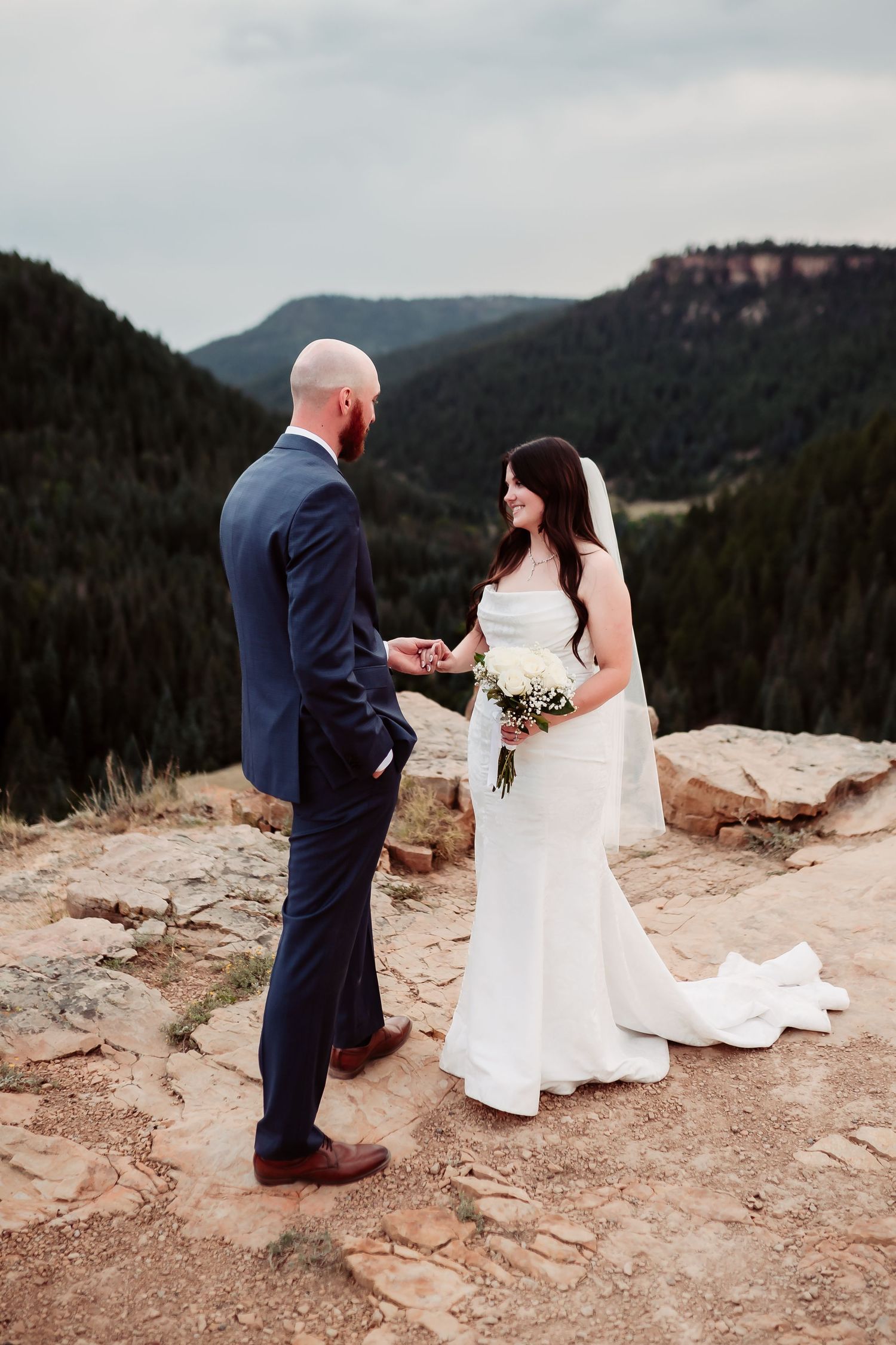 Couple exchanges vows during mountain-top ceremony with dramatic valley views in background.