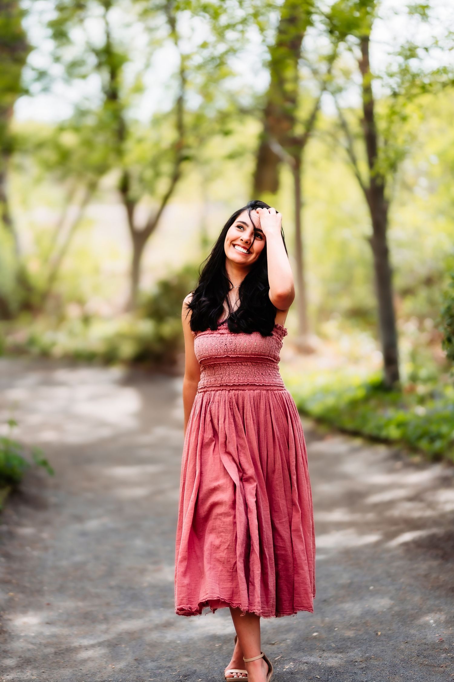 A flowing pink sundress adds elegance to a peaceful woodland path setting.