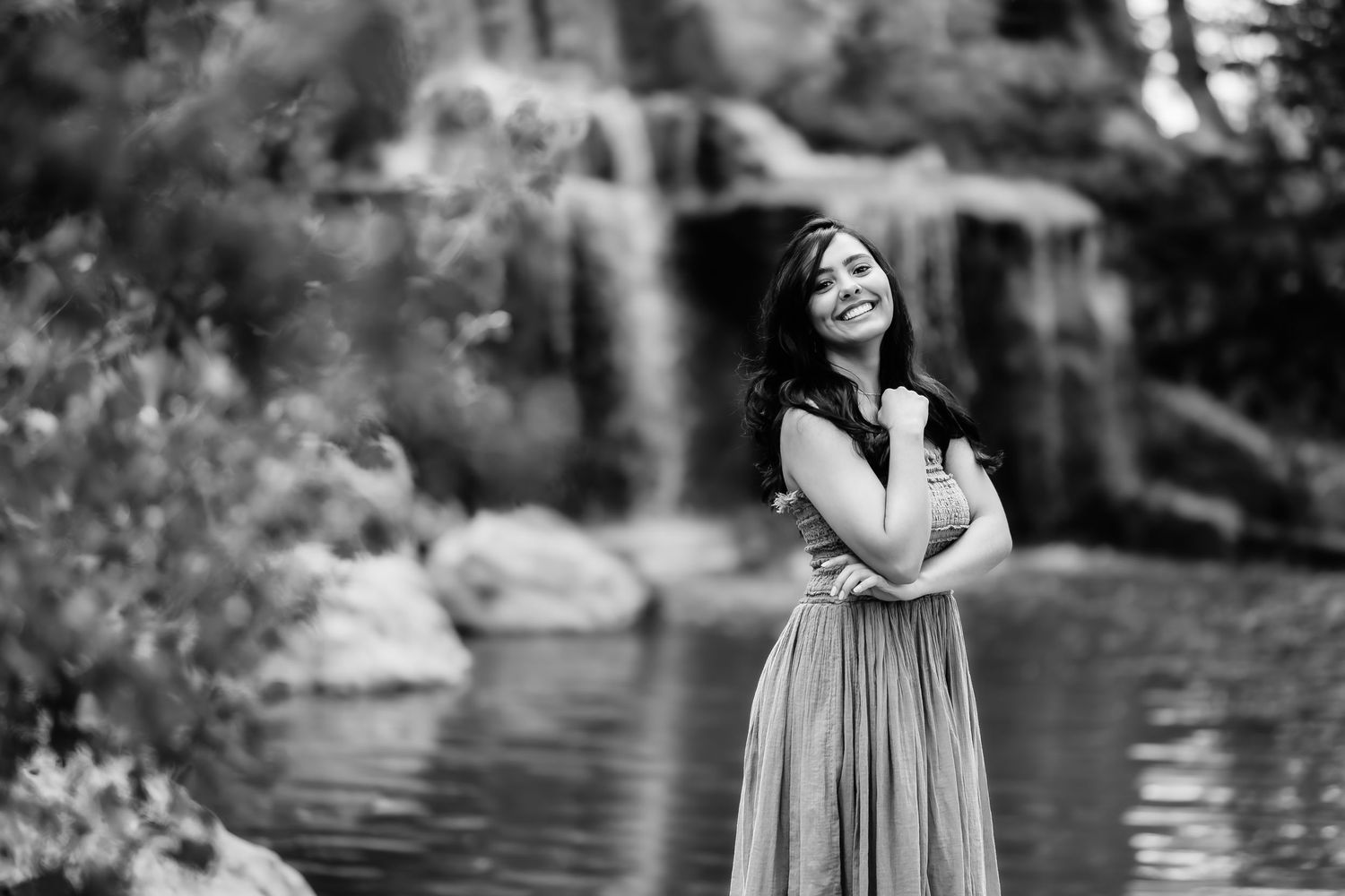 Black and white portrait of woman in flowing dress by lake.