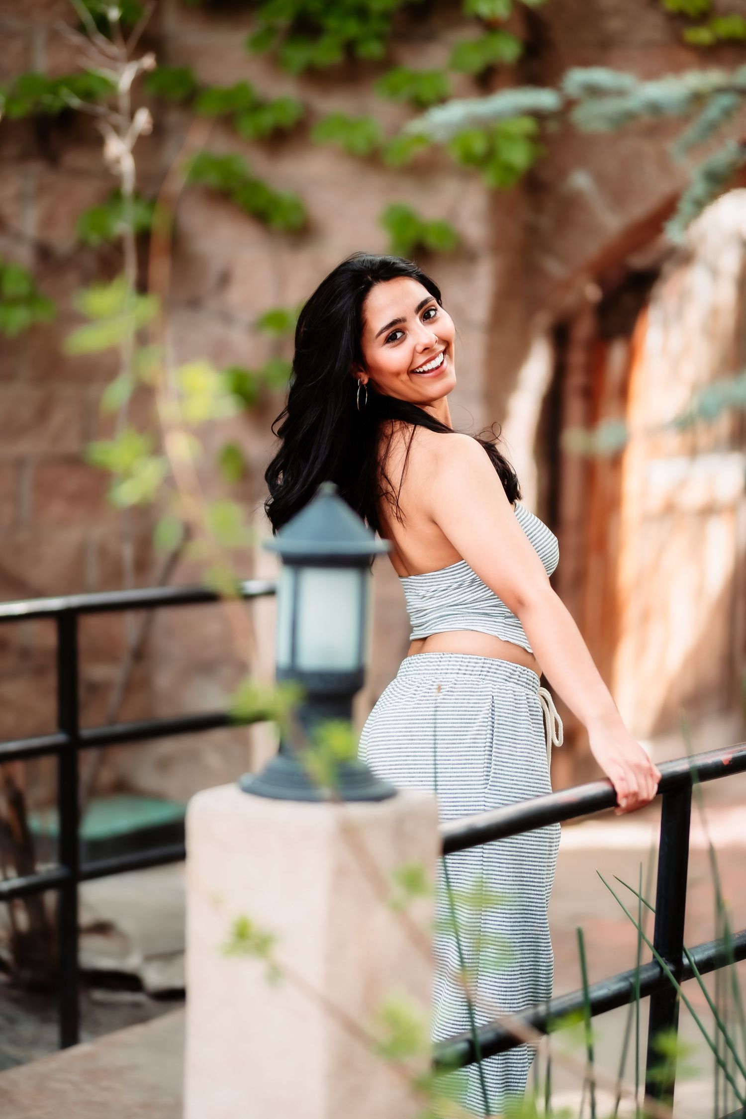 A person wearing athletic wear smiles while posing on stone steps with a lantern in the background.