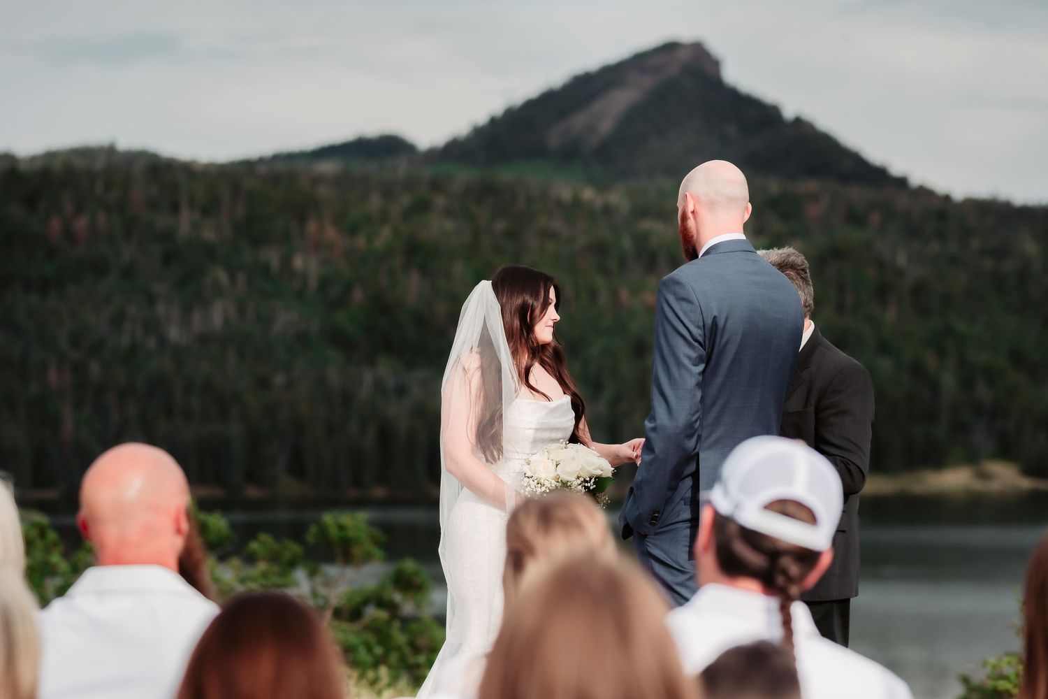 A wedding ceremony overlooking mountains with guests seated on chairs facing the proceedings.