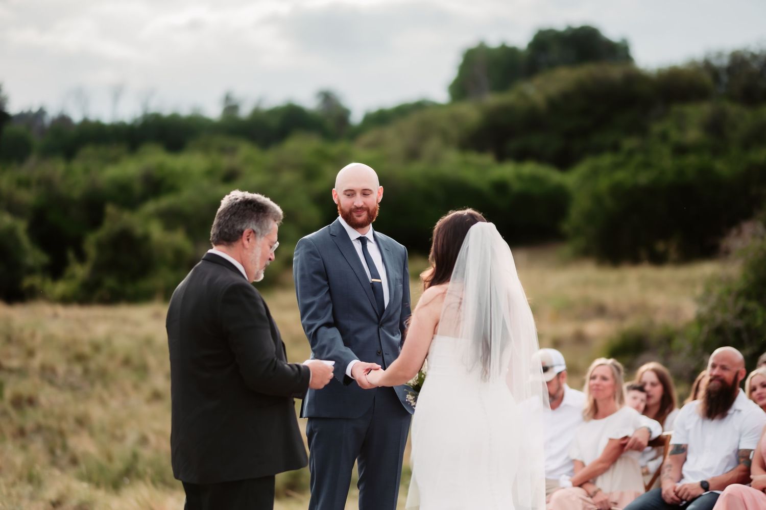 Candid wedding ceremony moments captured outdoors with a scenic waterfront backdrop.