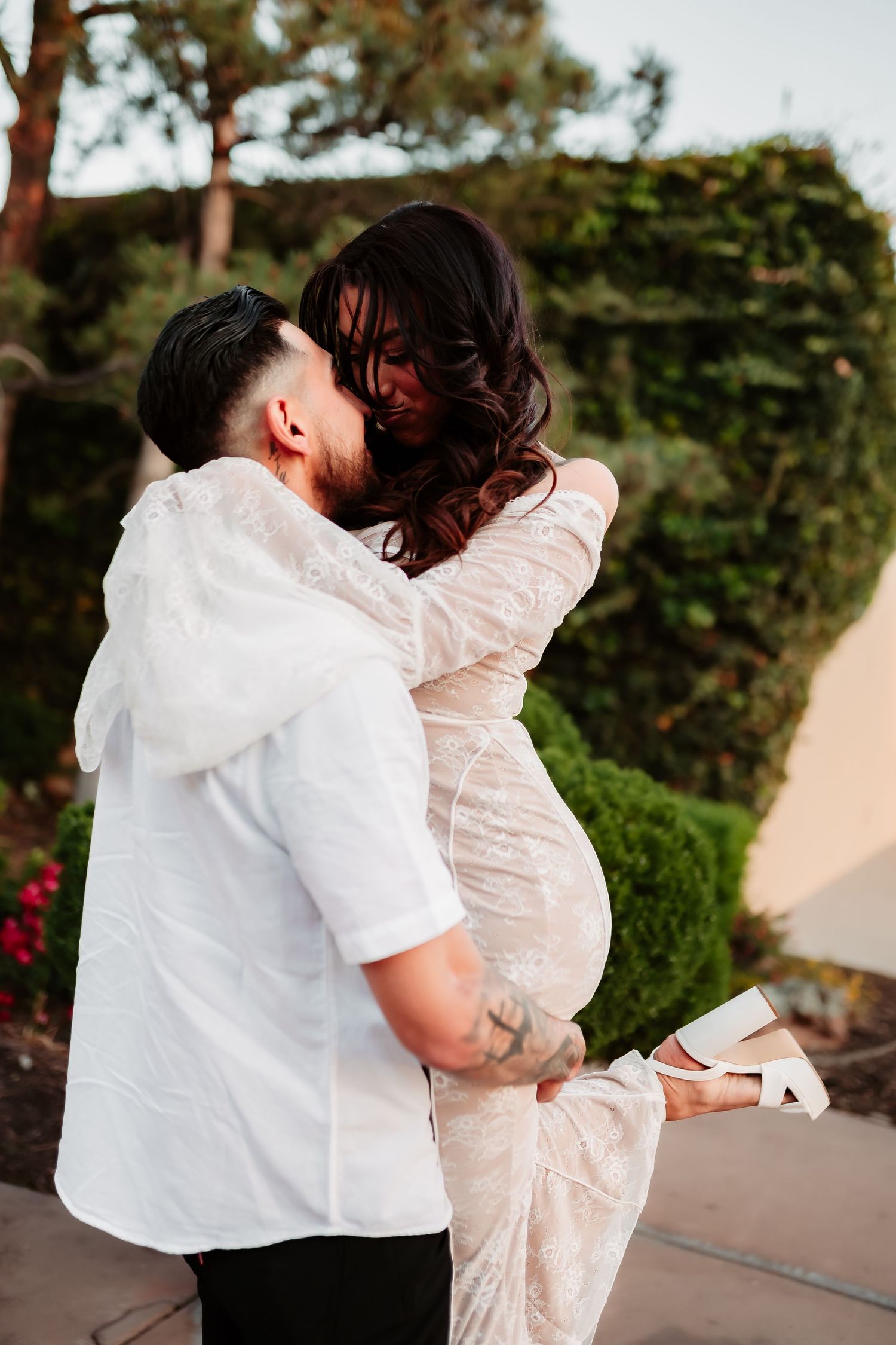A couple sharing an intimate moment in an outdoor garden setting.