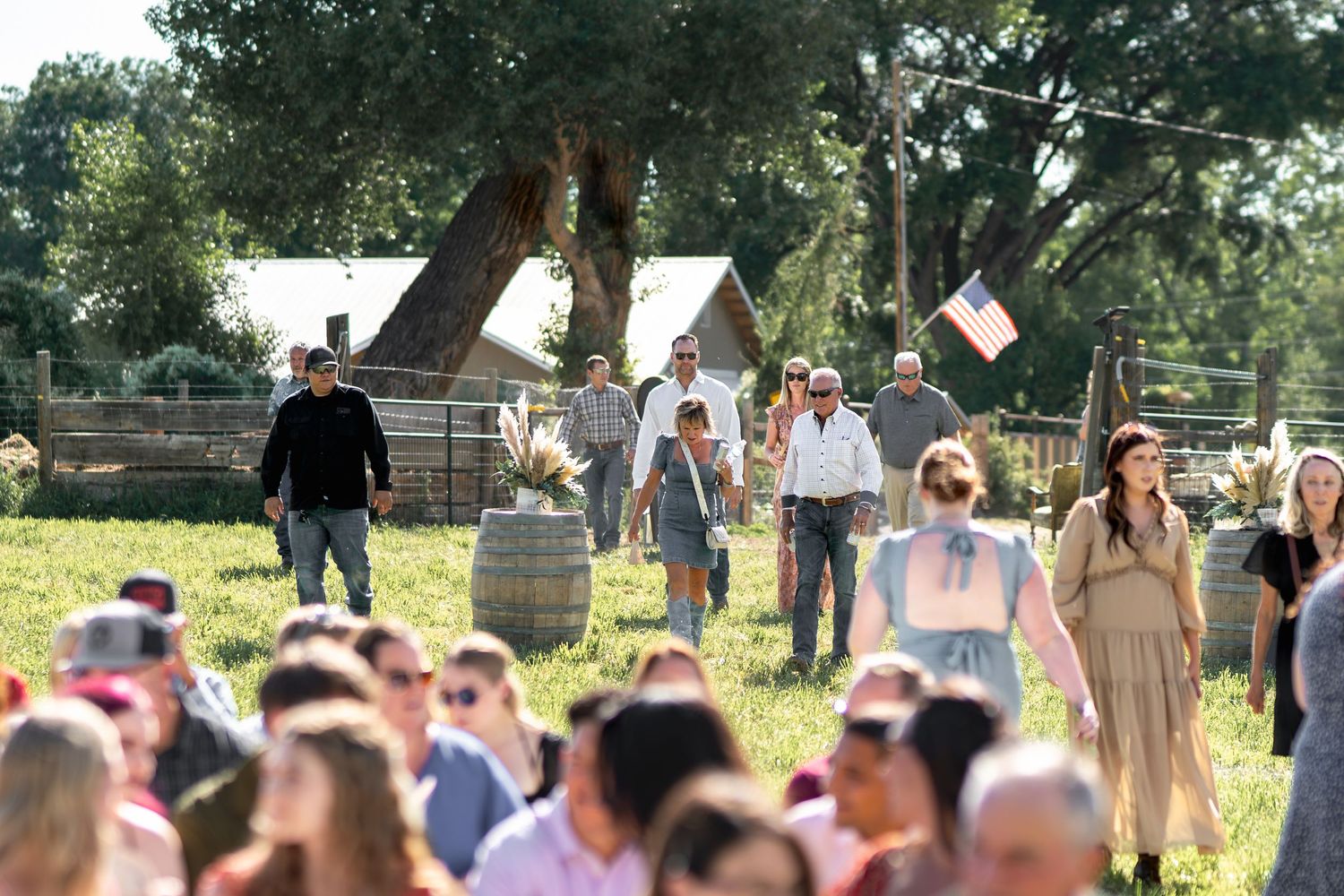 Large outdoor wedding ceremony with guests gathered under trees.