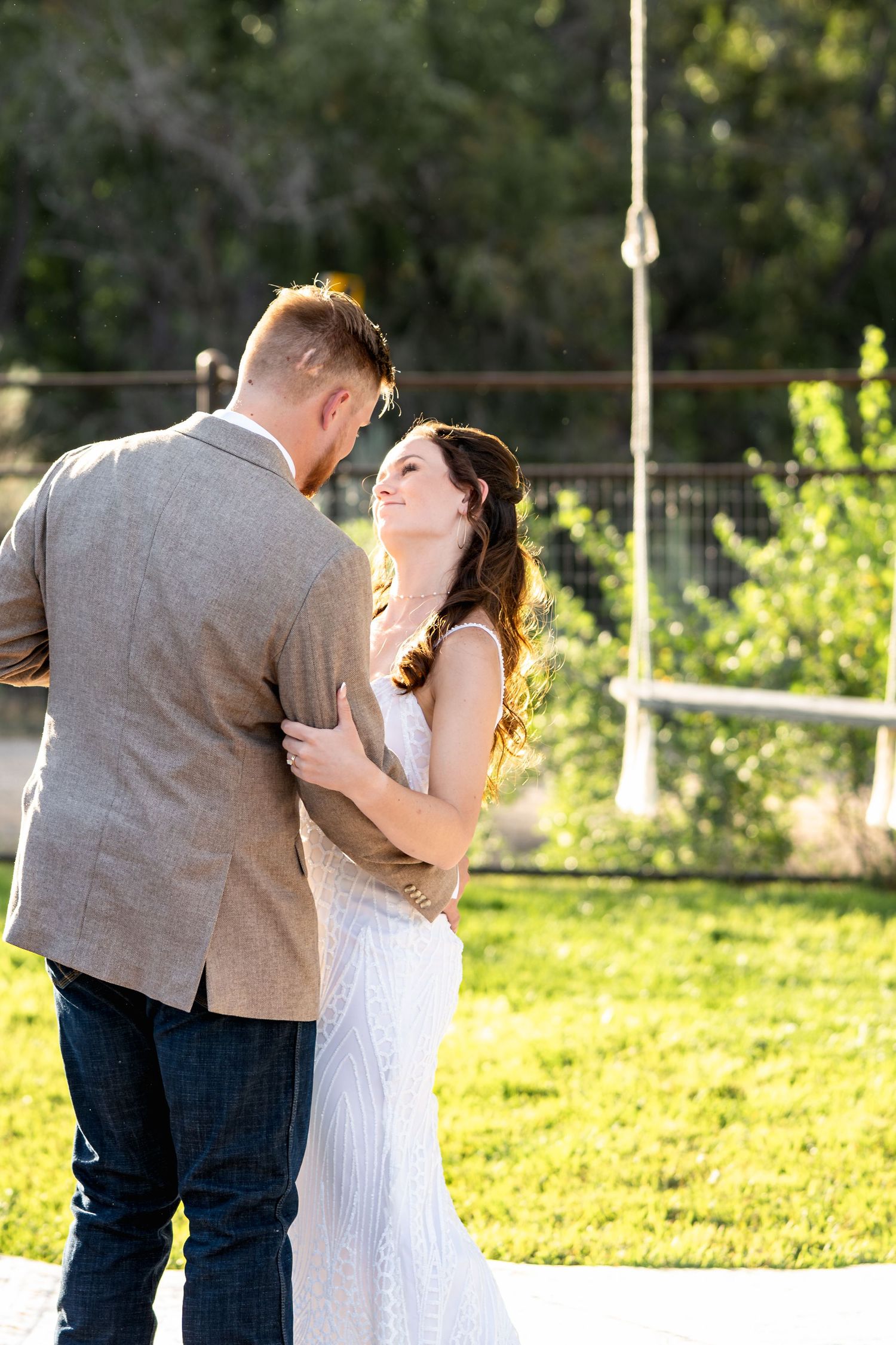 Newlyweds share a tender moment in golden sunlight on their wedding day.