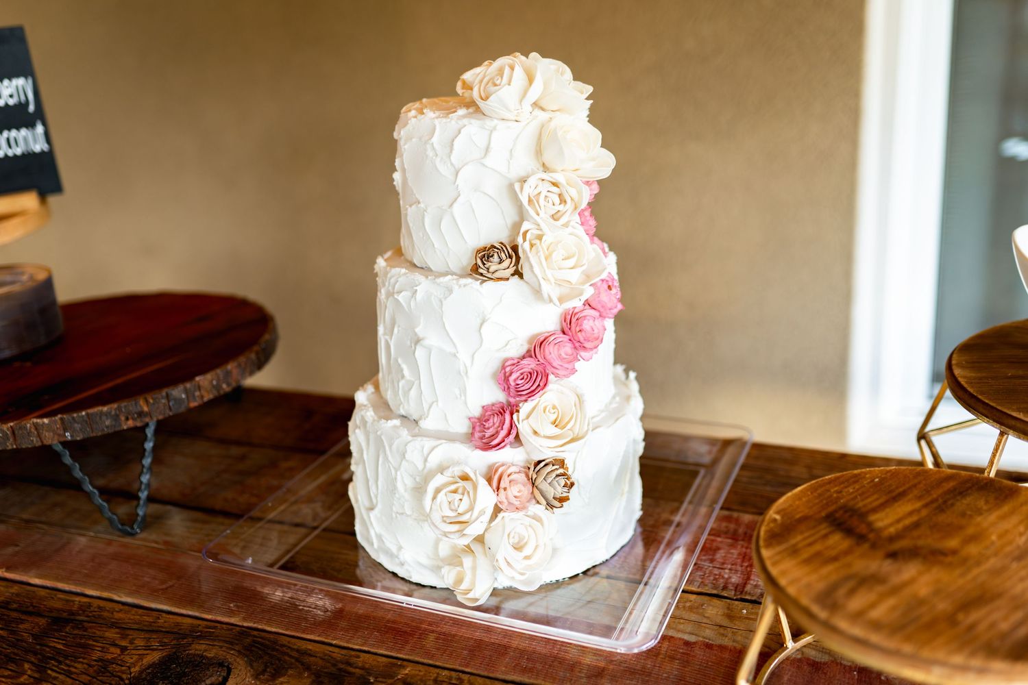 Elegant white wedding cake with delicate floral decorations displayed on a wooden table.