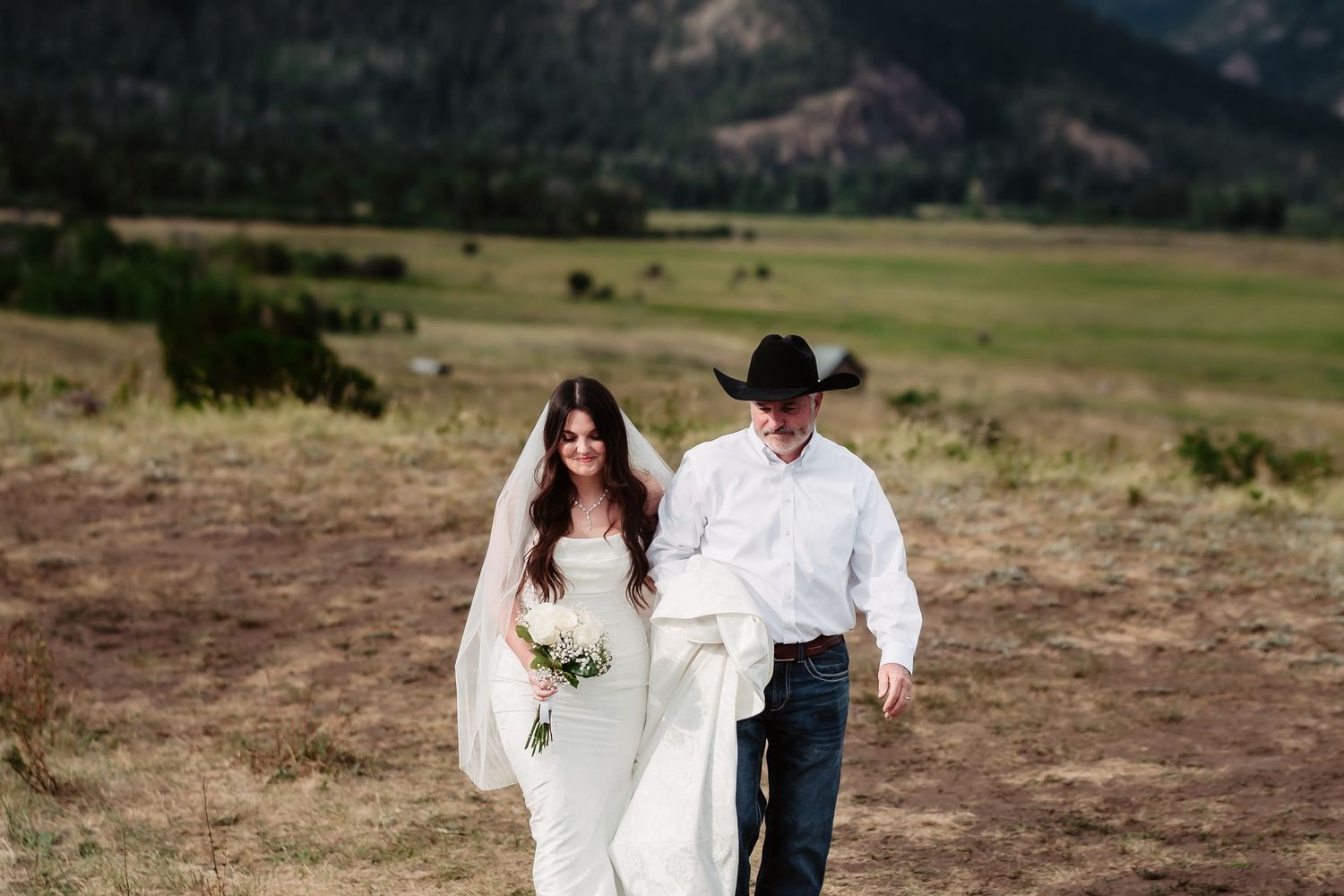 Couple walks together in scenic mountain field during their wedding day.