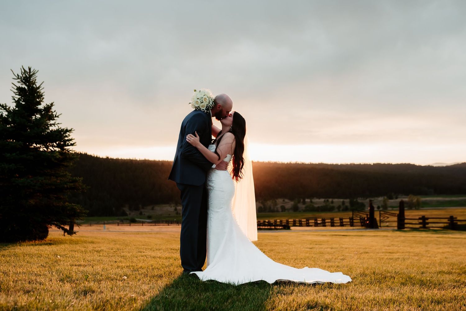 A romantic sunset silhouette of newlyweds sharing an intimate moment in a field.
