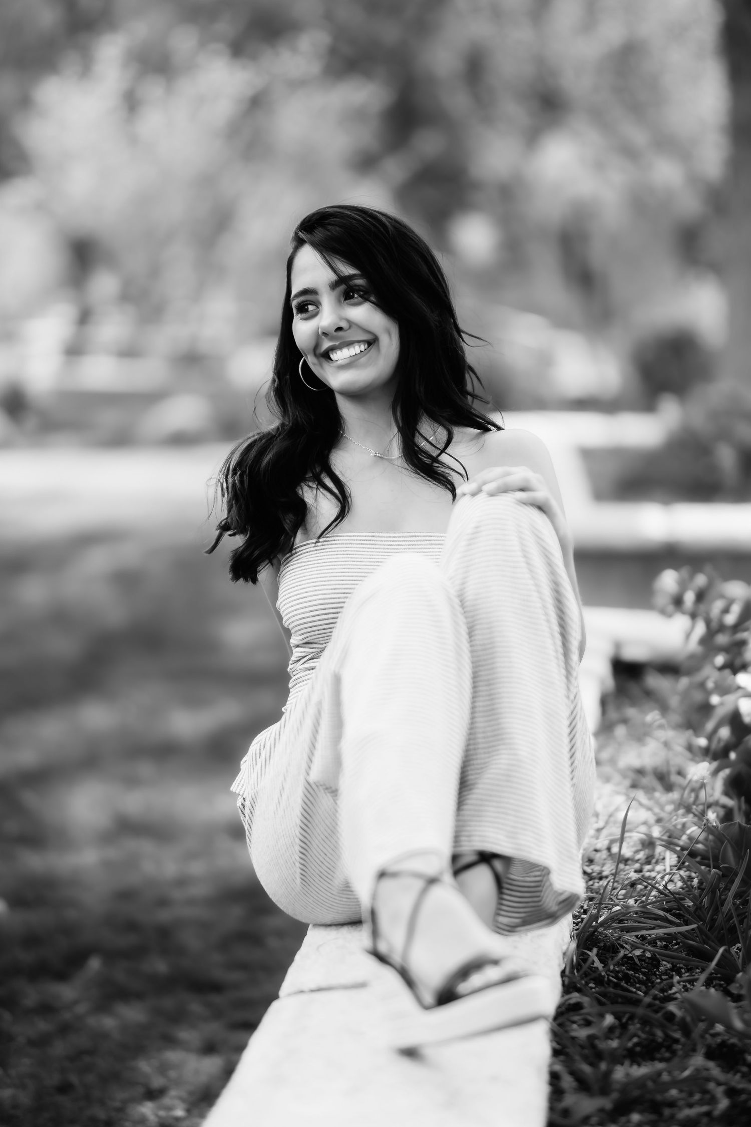 Cheerful outdoor portrait in black and white showing a person in light clothing against a natural backdrop.