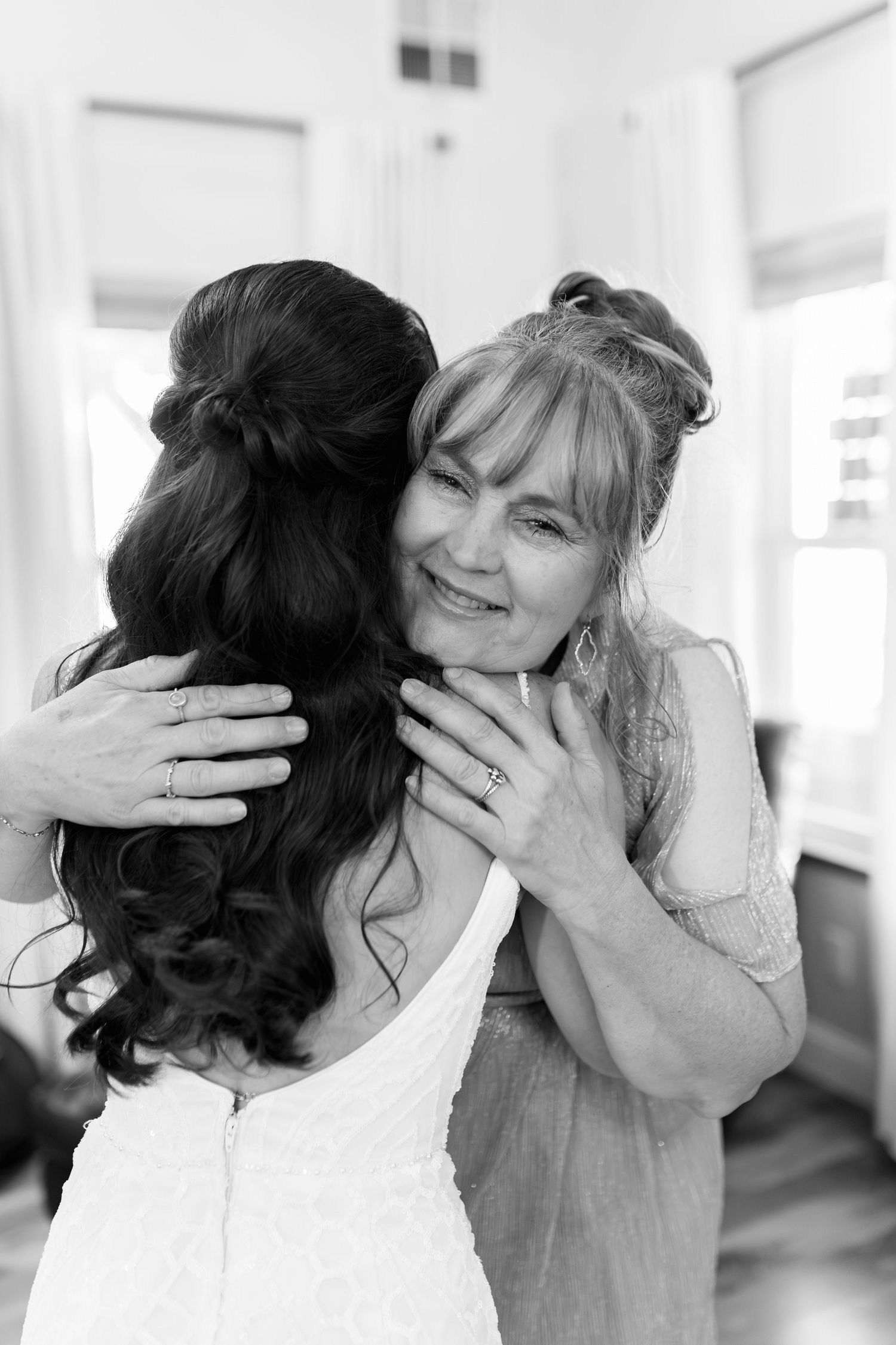 Black and white emotional embrace captured during wedding preparations.