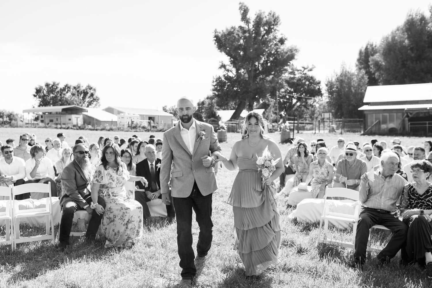Vintage-style black and white photo of a wedding ceremony in a rustic outdoor setting.