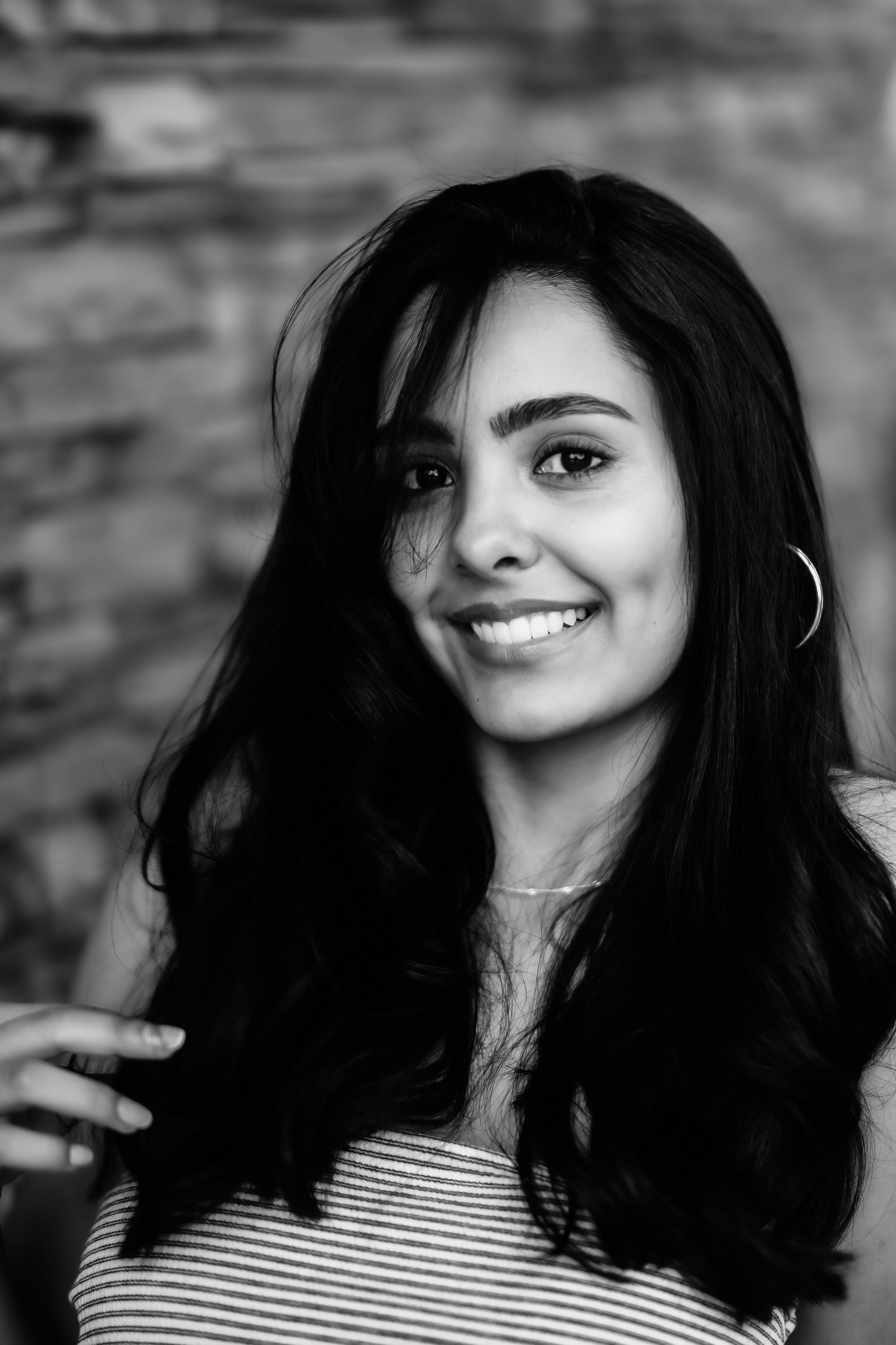A black and white closeup portrait against a textured brick wall background.