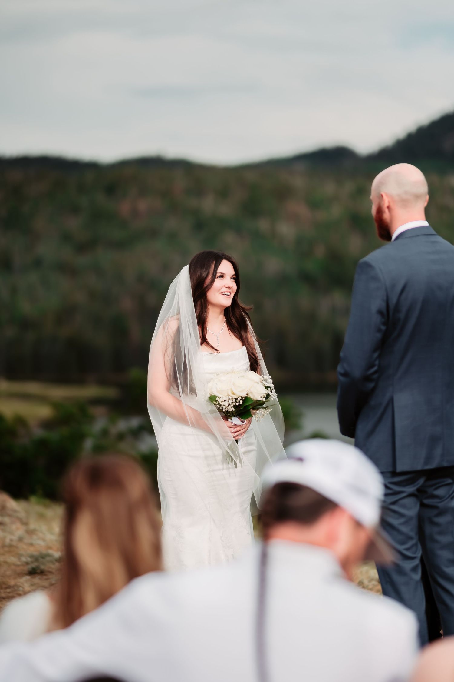 Wedding ceremony with scenic mountain backdrop as couple exchanges vows in an outdoor setting.