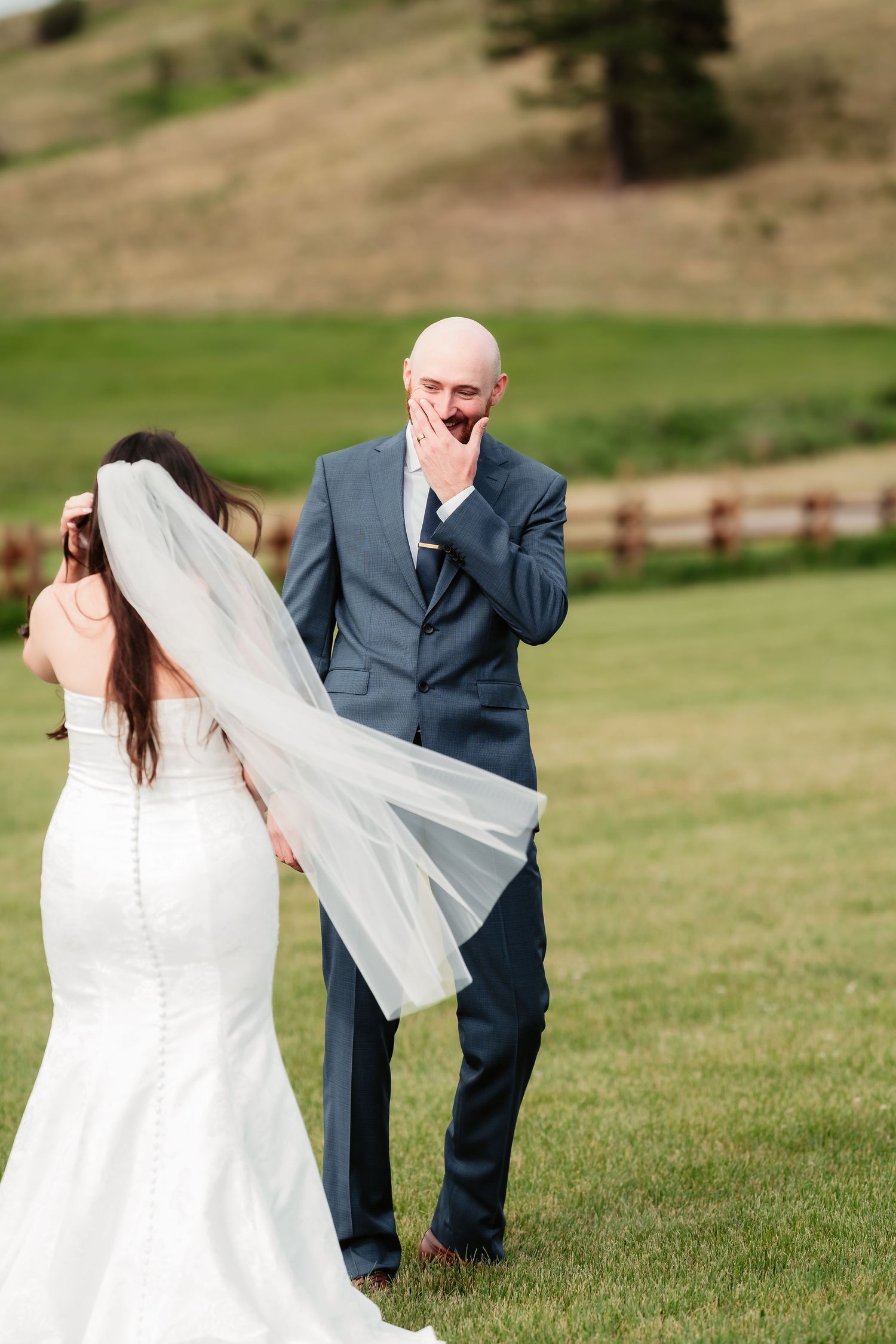 Emotional first look moment between wedding couple in mountain field setting.