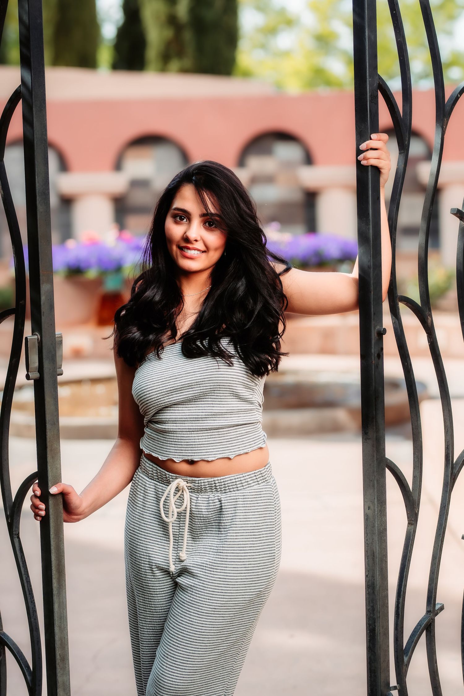 A casual portrait by a decorative gate shows someone in comfortable grey loungewear with flowing dark hair.