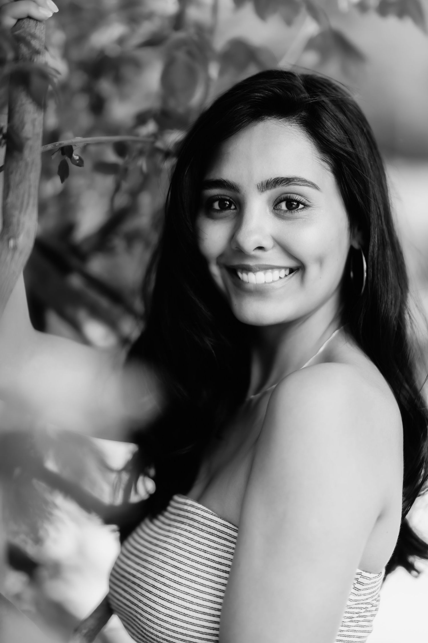 Black and white close-up portrait showing person in striped top near foliage.