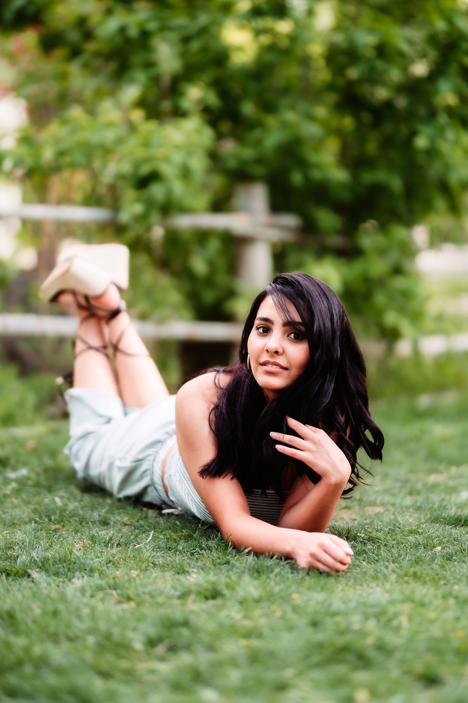 A woman in white lounges on lush grass during an outdoor portrait session.