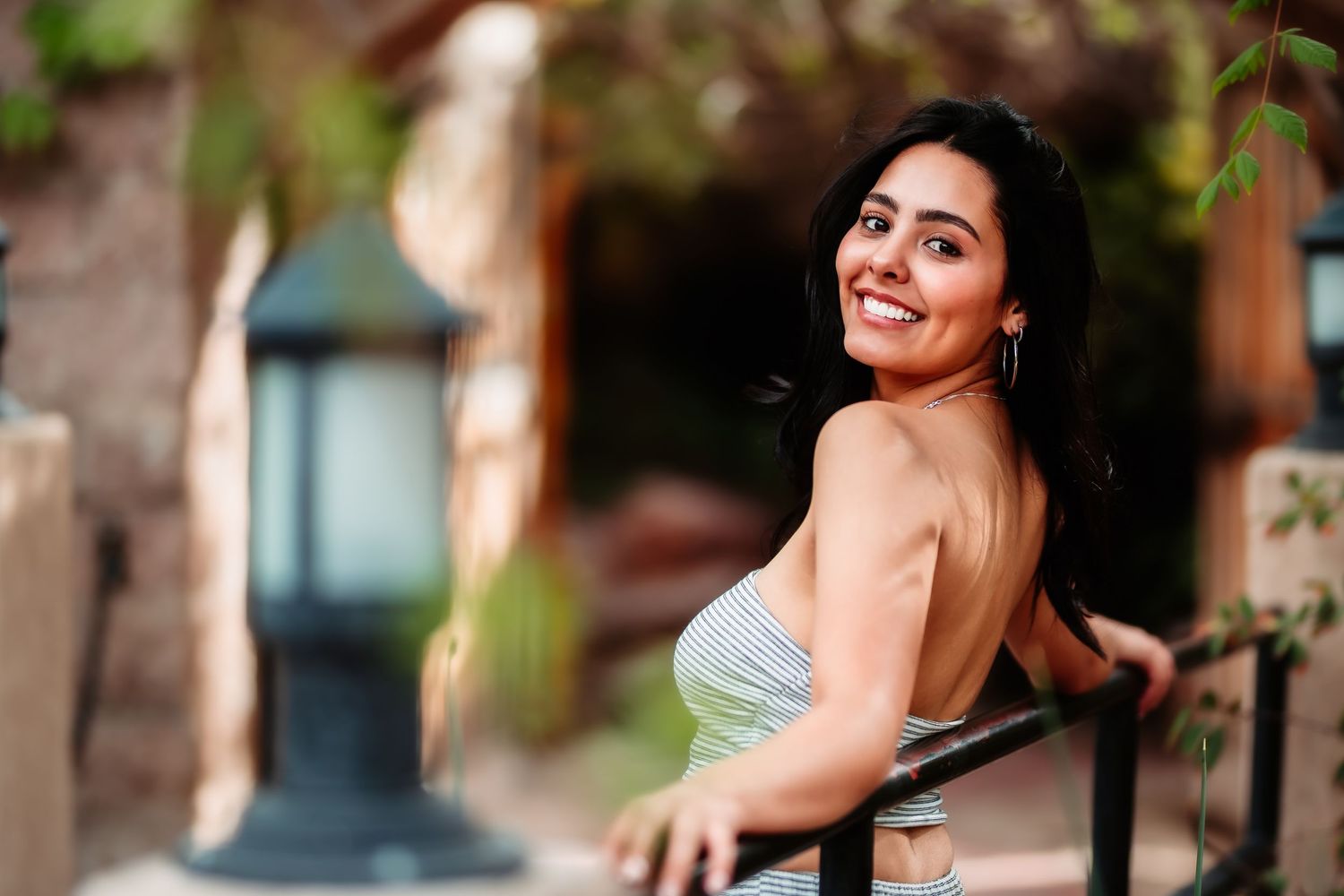 A casual outdoor portrait against stone architecture with a decorative lamp in the background.