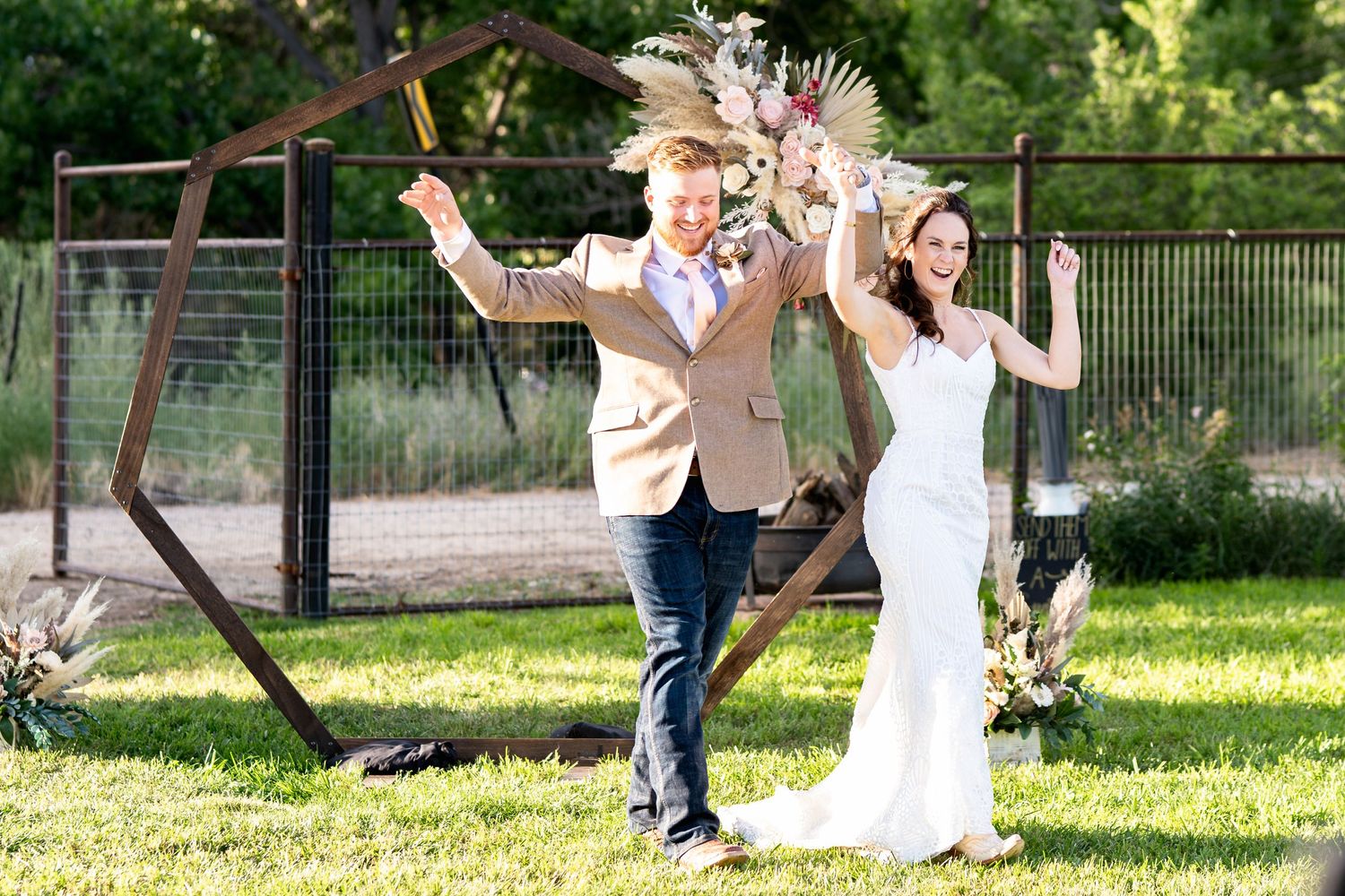 A couple celebrates during their outdoor garden wedding ceremony with enthusiastic dance moves.