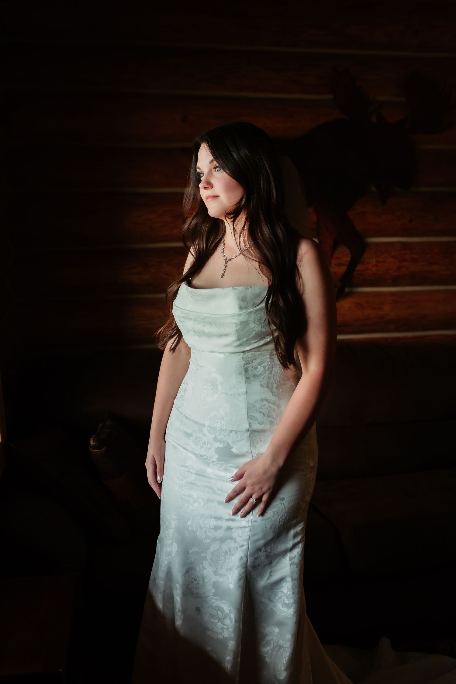 Close-up details of a white lace wedding dress against a dark wooden background.