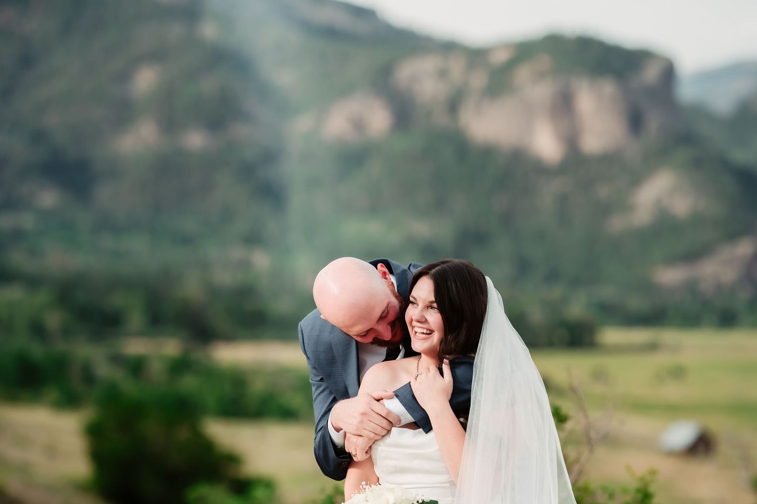 Romantic wedding moment photographed against scenic mountain backdrop.