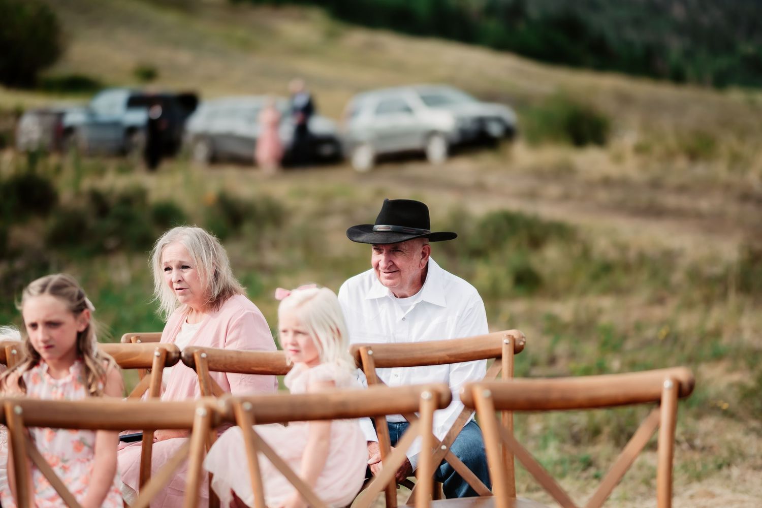 Wooden folding chairs arranged in rows for an outdoor wedding ceremony in a rustic field setting.