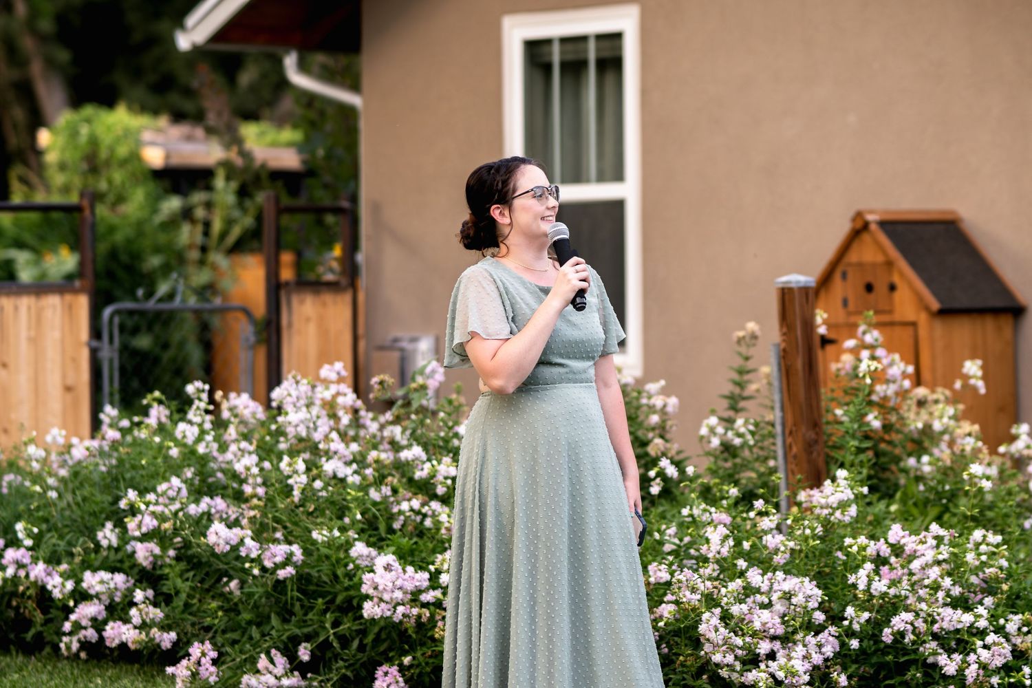 Speaker shares emotional moment in garden setting with blooming flowers.