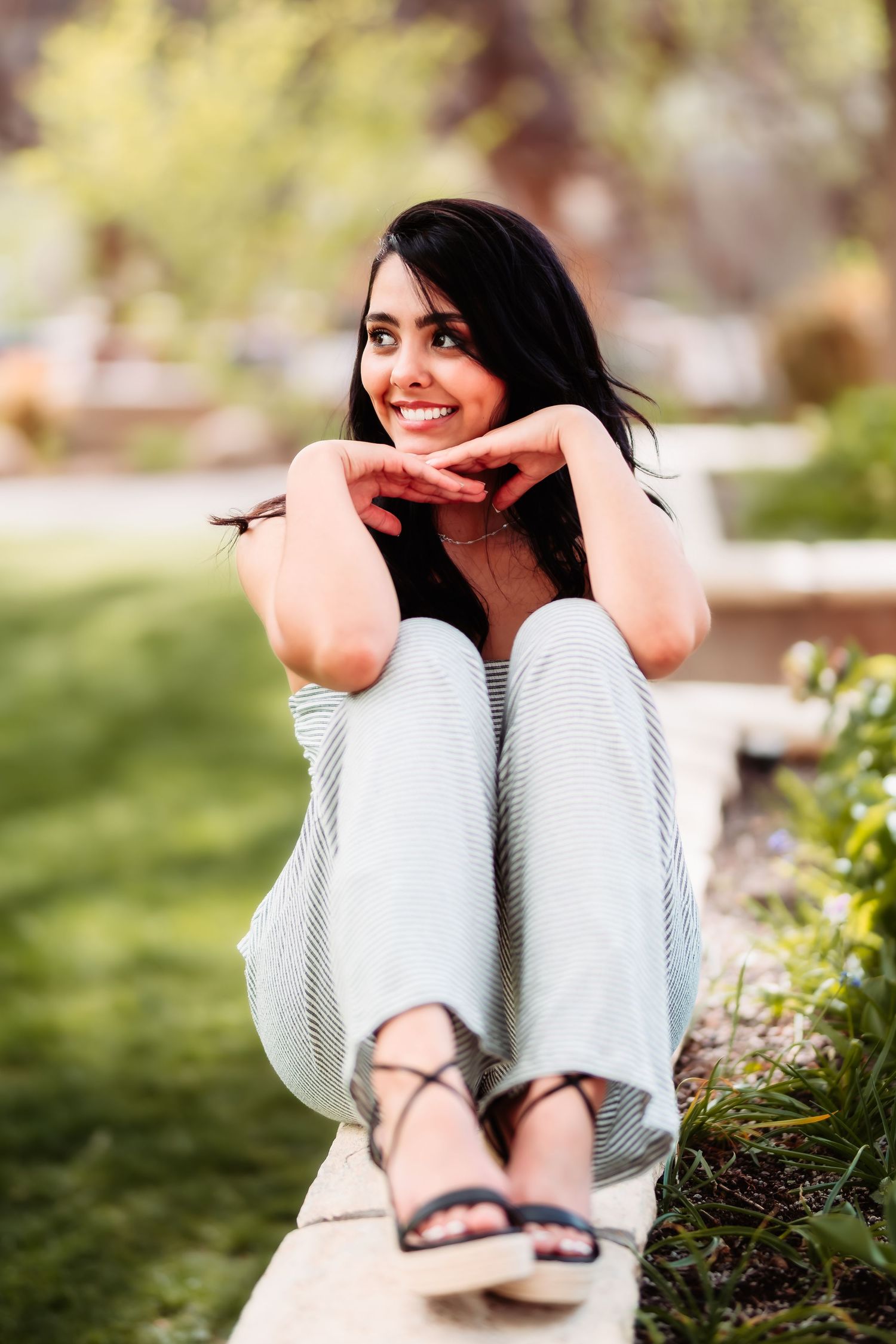 Casual outdoor portrait showing relaxed pose on wooden bench in comfortable gray attire.