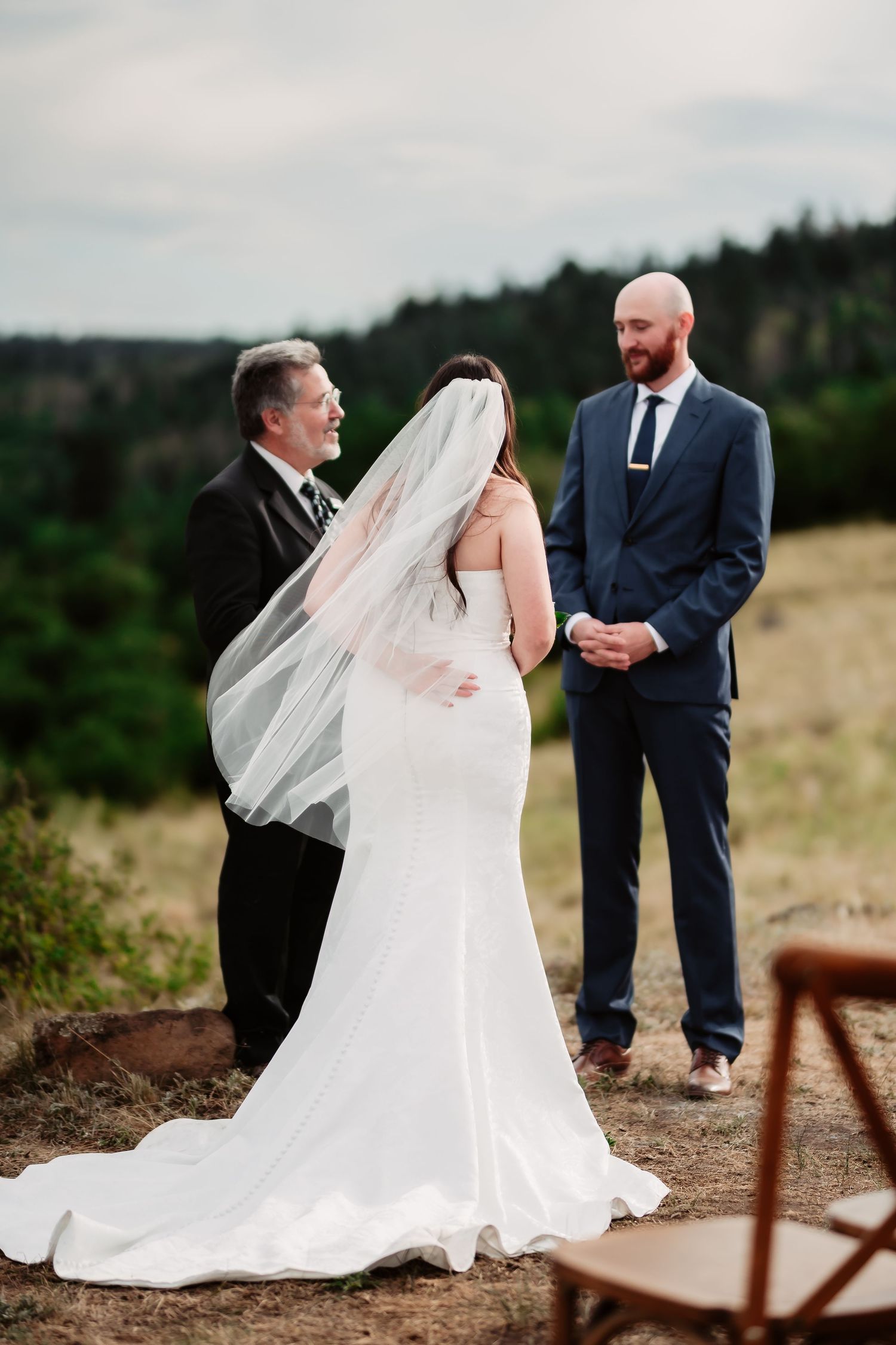 Sequence of wedding ceremony photos showing a couple exchanging vows on a hilltop with flowing white dress and veil.
