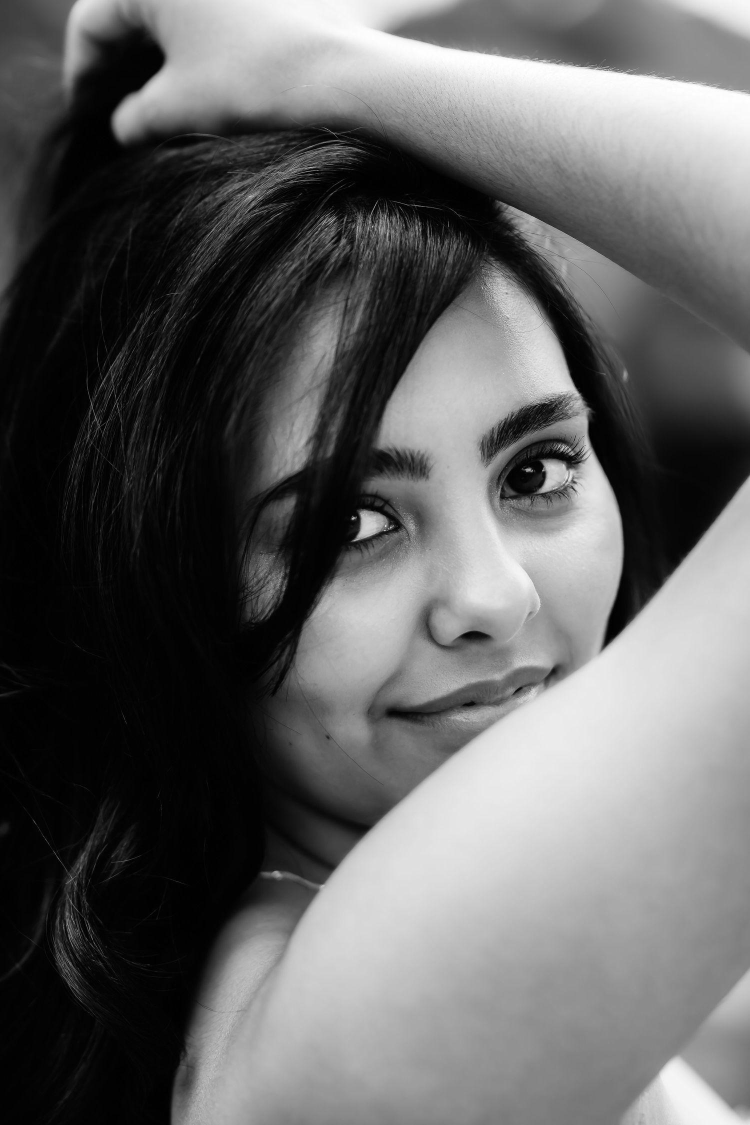 An artistic black and white closeup portrait showing expressive eyes and a gentle smile.