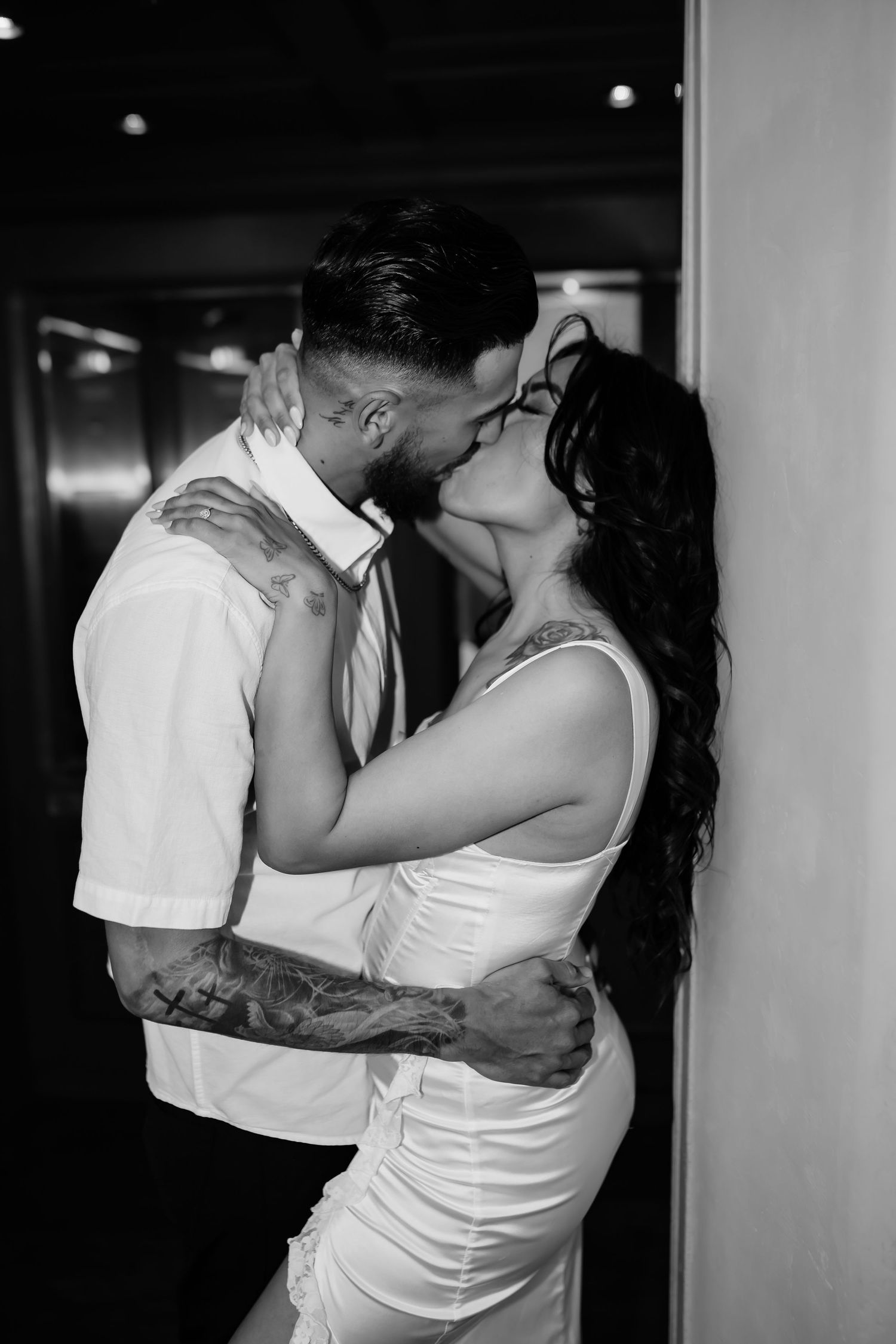 An intimate black and white portrait of a couple sharing a romantic kiss.