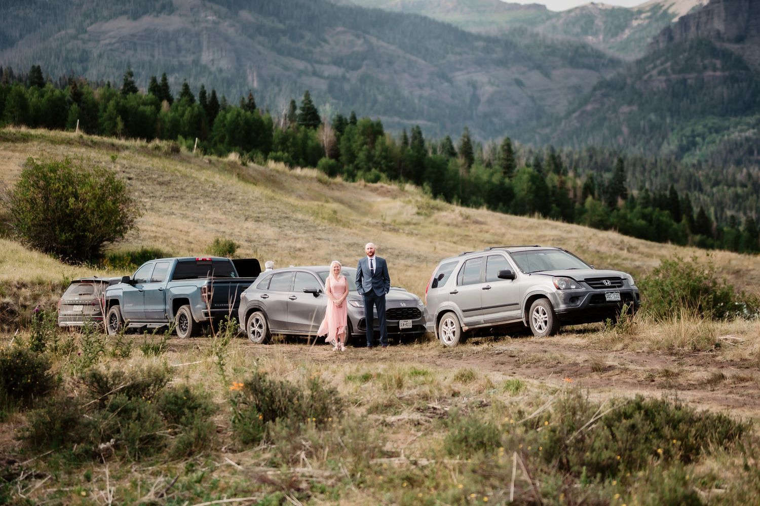Panoramic view of parked cars and mountain landscape at outdoor wedding venue.