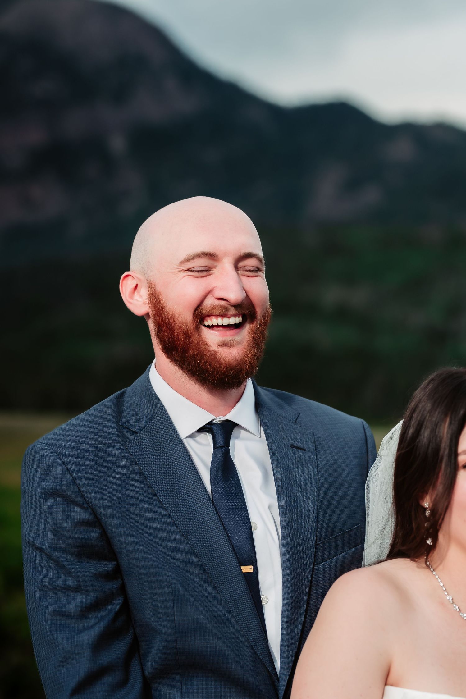 A joyful moment captured against a mountainous backdrop during an outdoor wedding ceremony.
