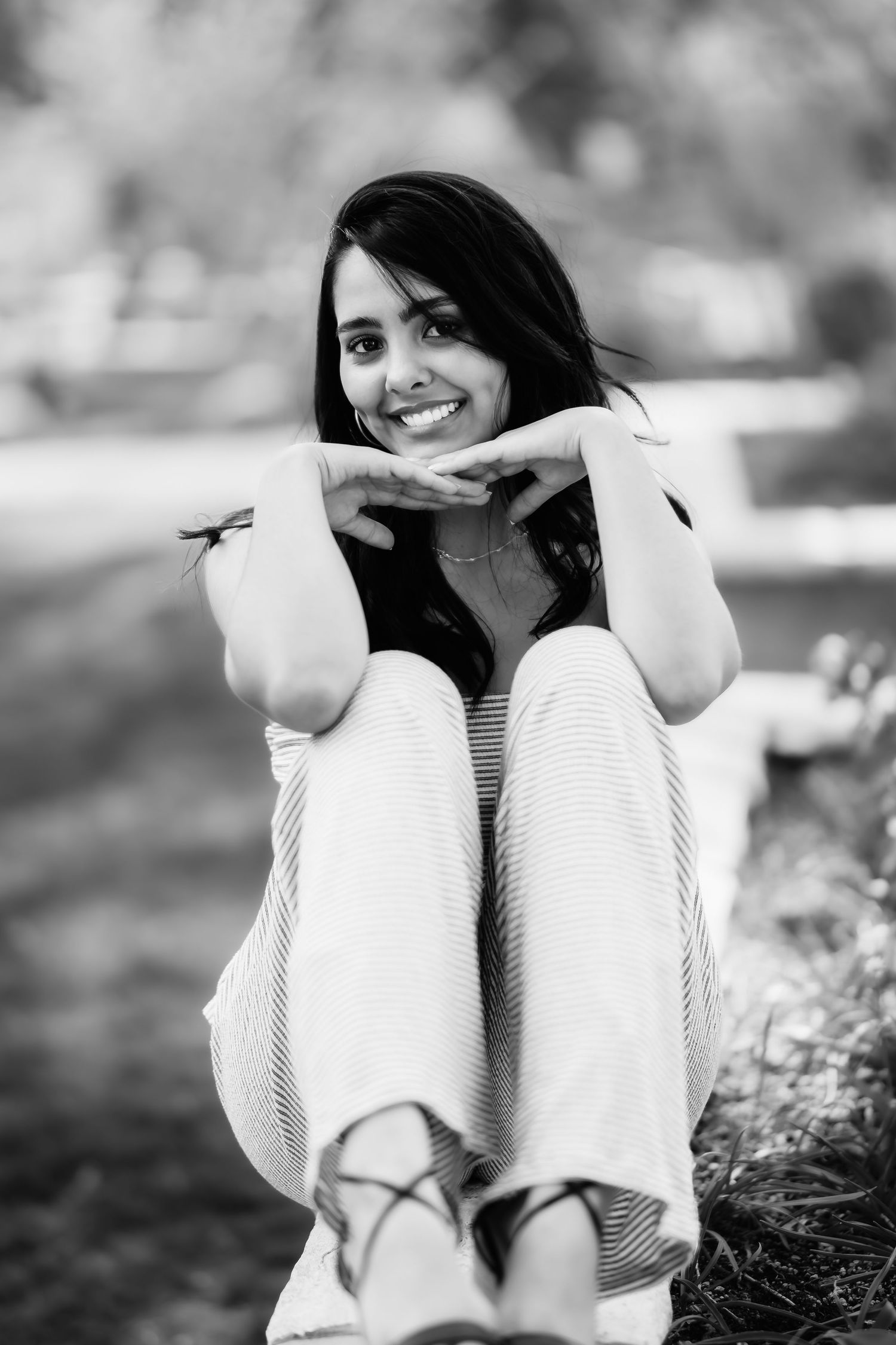 A cheerful black and white portrait showing relaxed pose with striped top and light pants.