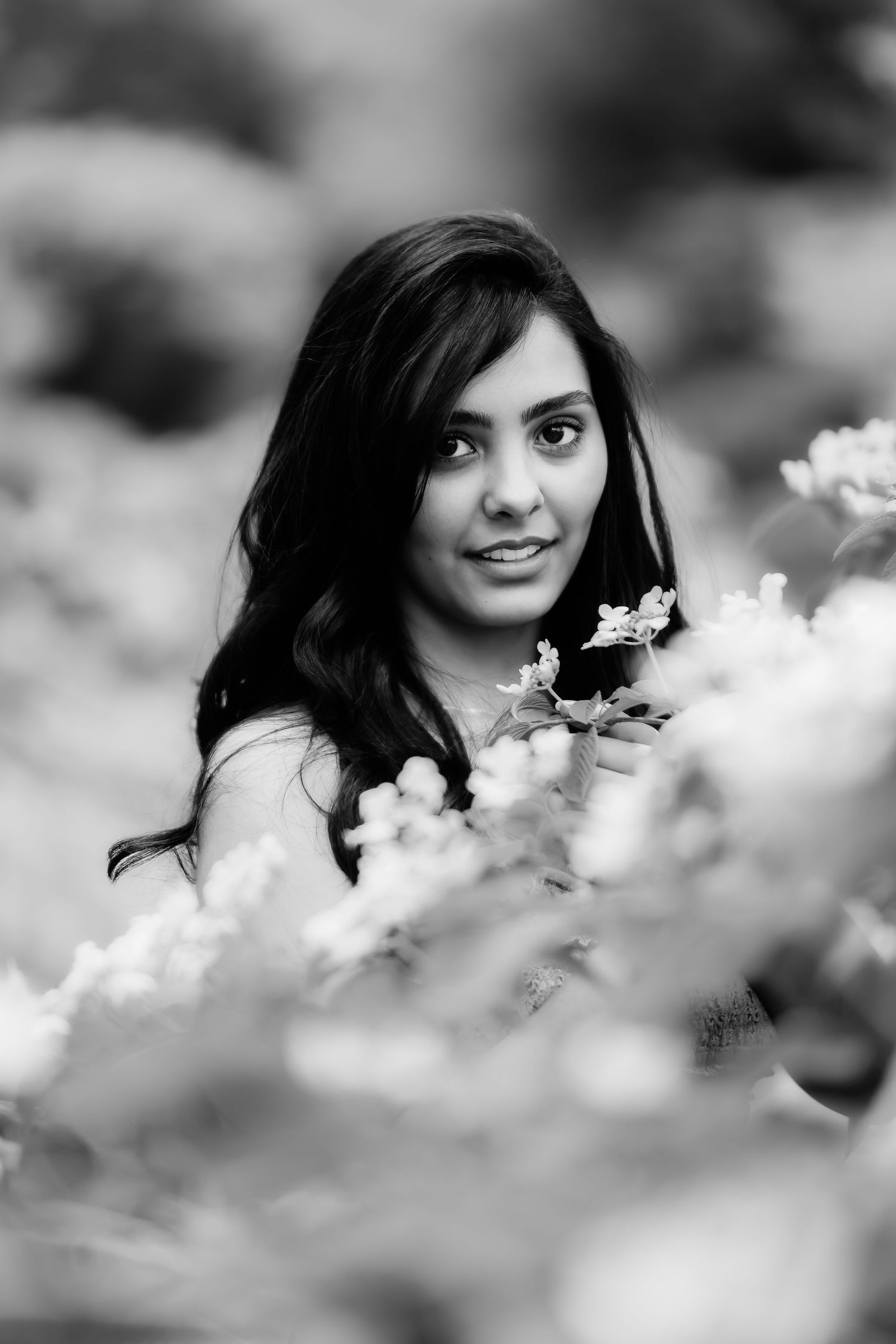 Artistic black and white portrait framed by delicate white flowers in soft focus.