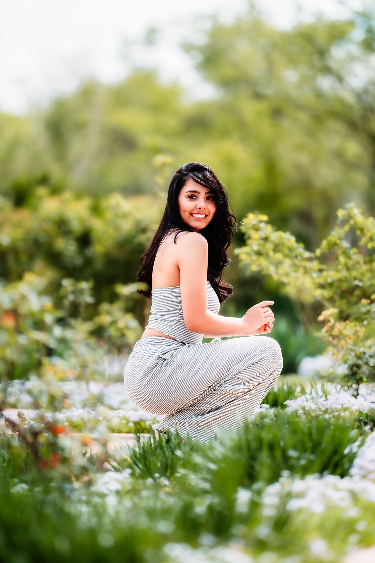 A relaxed portrait in a garden setting with white flowers and green foliage.