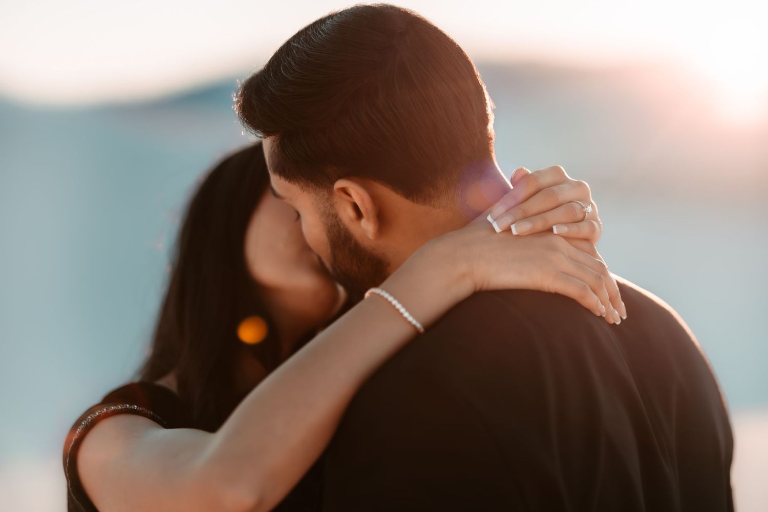 Romantic couple embracing in soft sunset light during intimate outdoor moment.